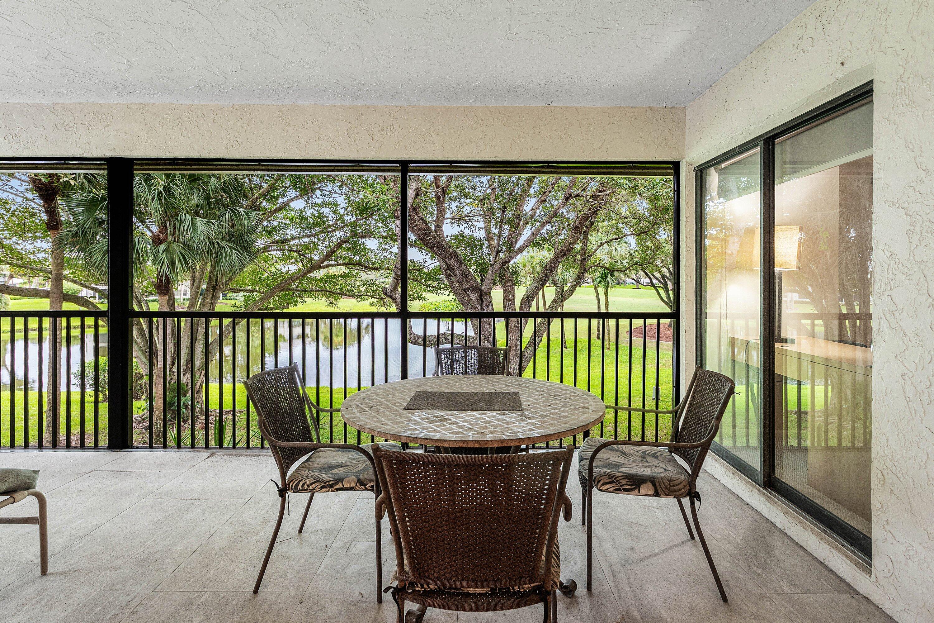 Screened-in patio featuring tile flooring, black metal railing, and sliding glass door entry