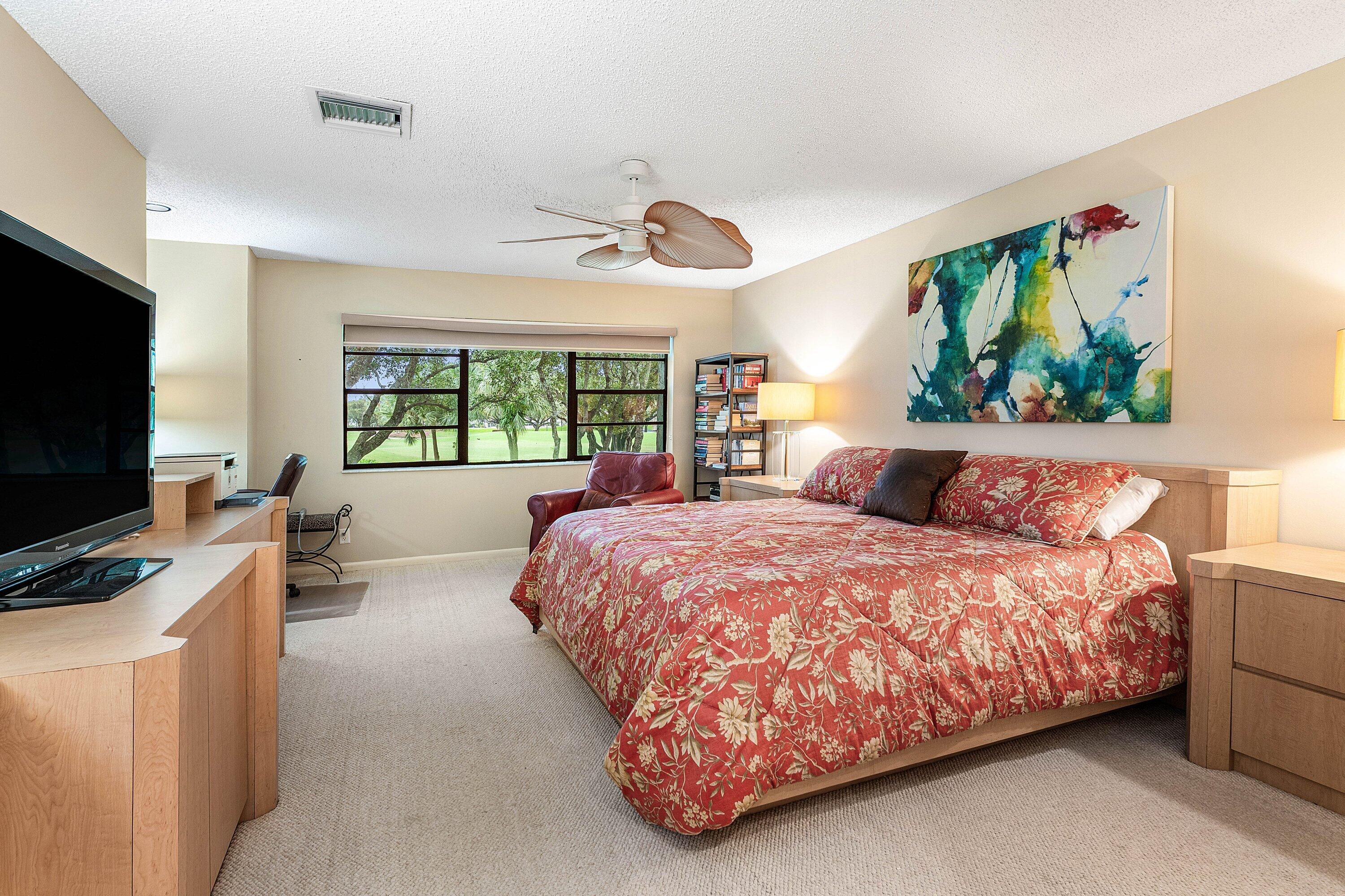 Neutral-toned carpeting, ceiling-mounted paddle fan, built-in cabinetry, and multi-pane windows
