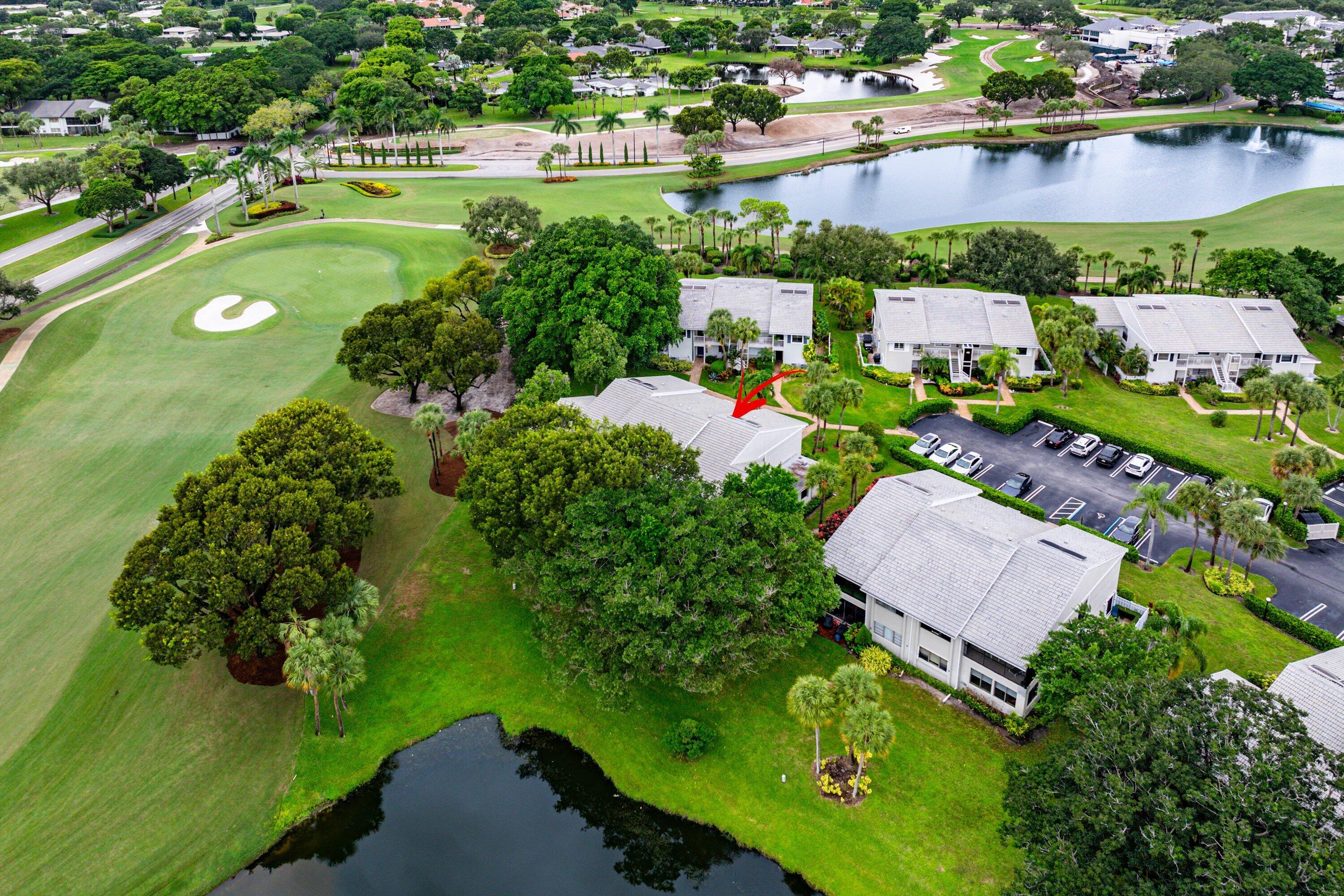 Aerial perspective featuring multi-story residential architecture, shingled roofing, mature landscaping, and proximity to water and golf course terrain