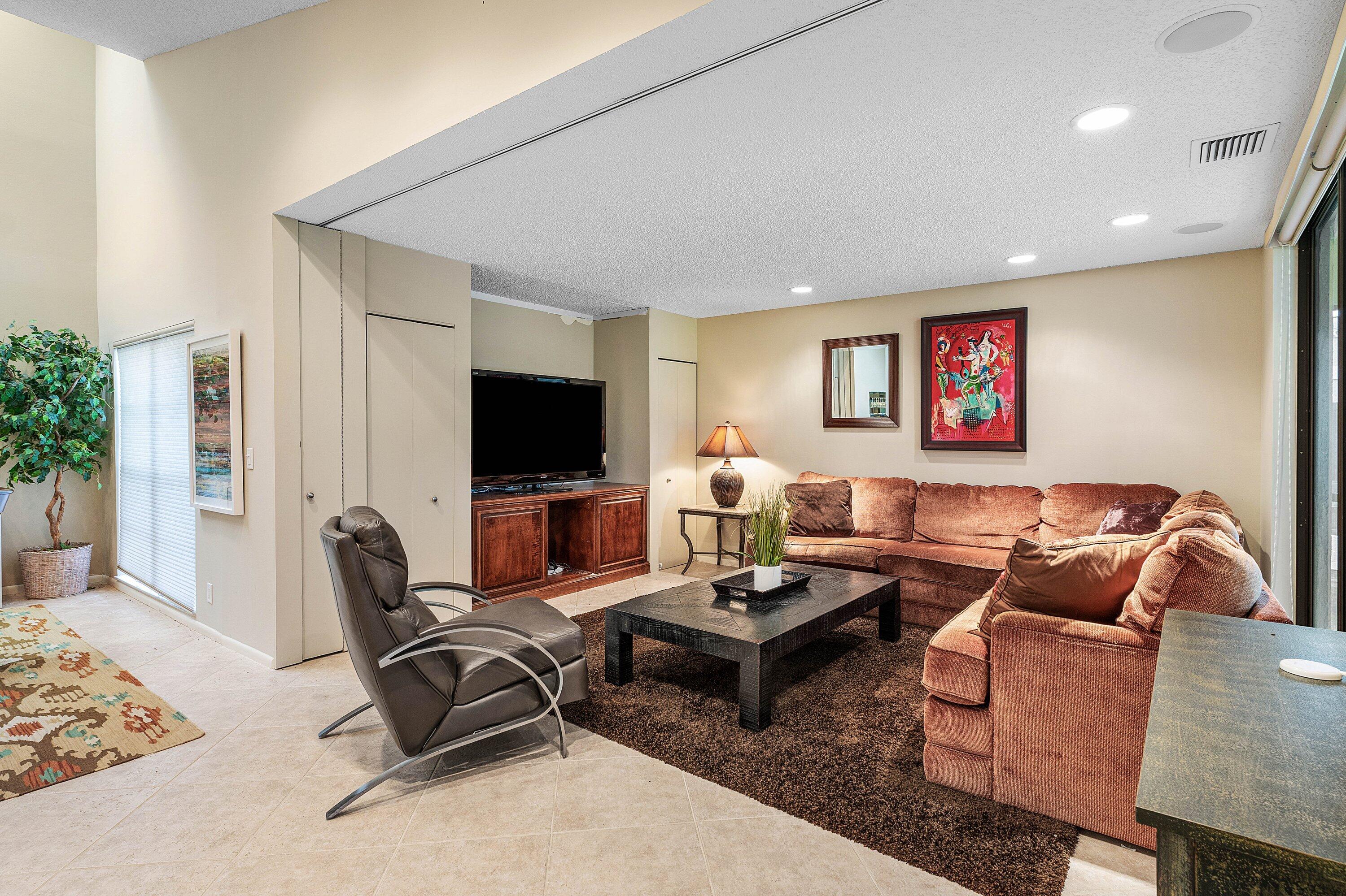 Living space featuring vaulted ceilings, recessed lighting, tile flooring, and built-in cabinetry