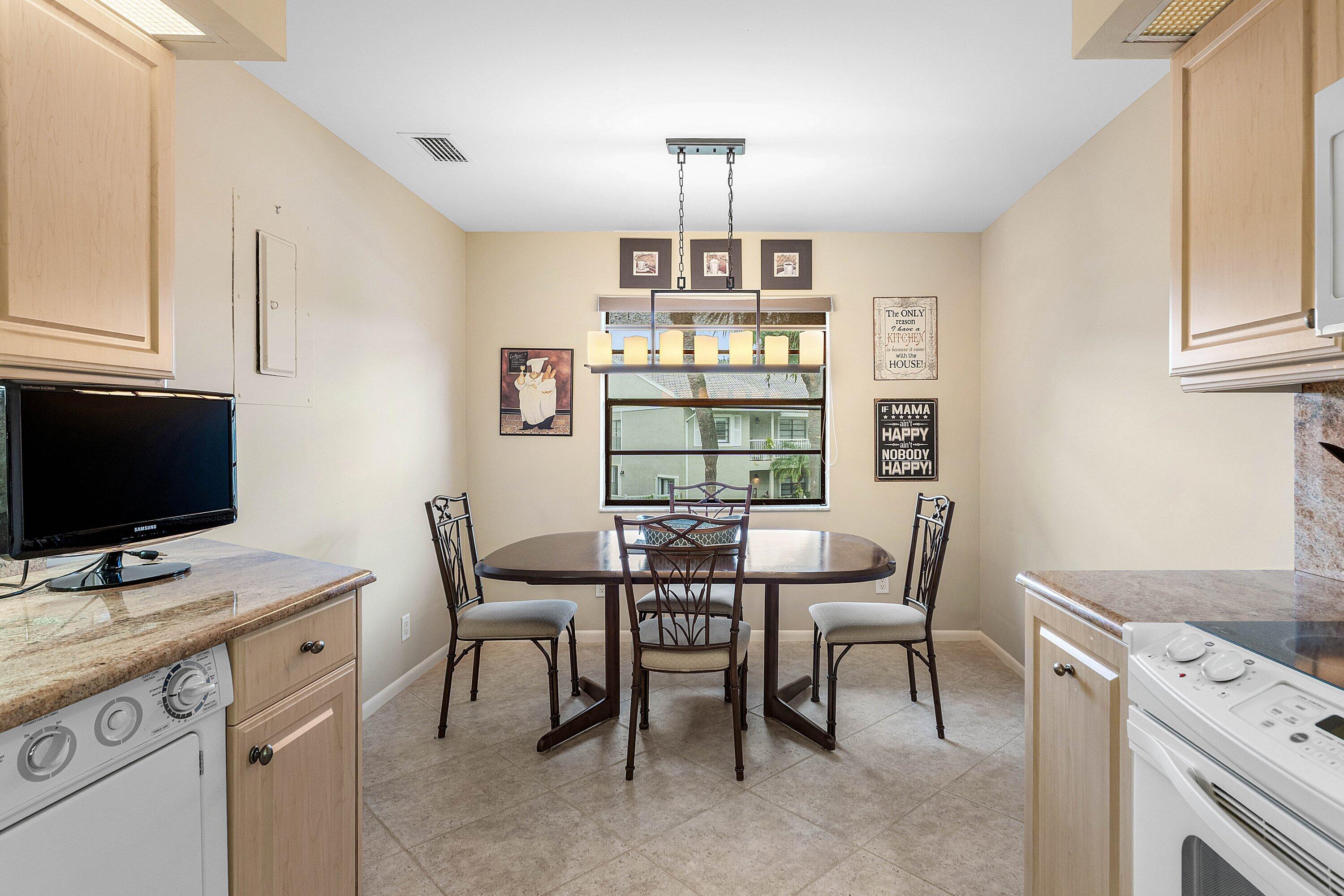 Kitchen featuring light wood-finish cabinetry, natural stone countertops, tile flooring, and a linear multi-light pendant fixture