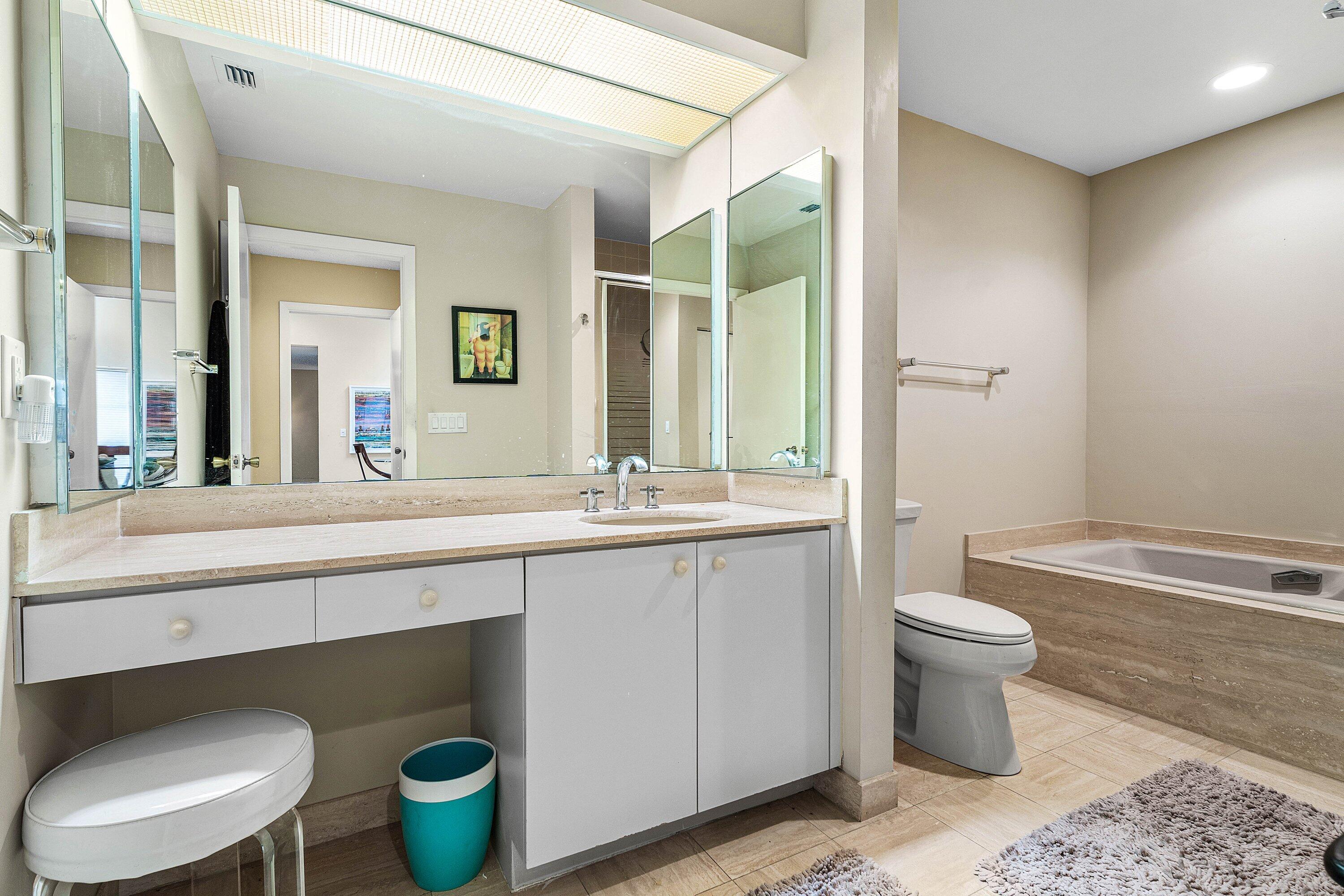 Vanity featuring a stone-composite countertop, dual-mirrored wall panels, integrated recessed lighting, and a drop-in sink