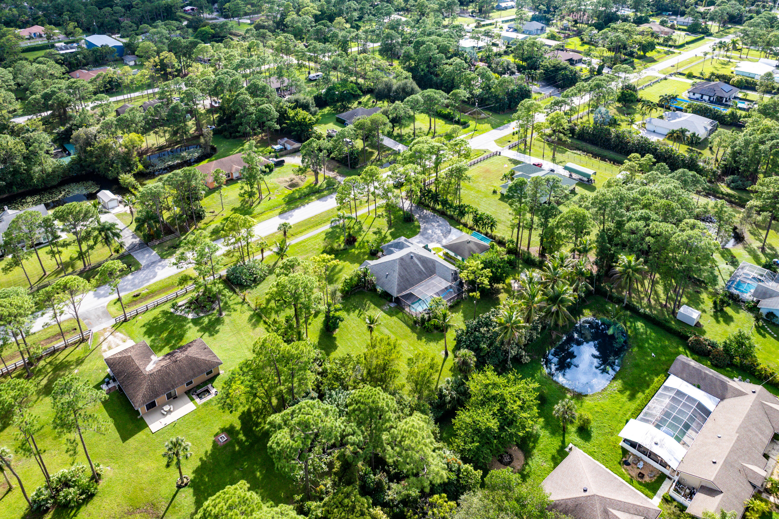 Aerial perspective featuring expansive residential lots, mature tree canopy, integrated ponds, and multi-pitched rooflines