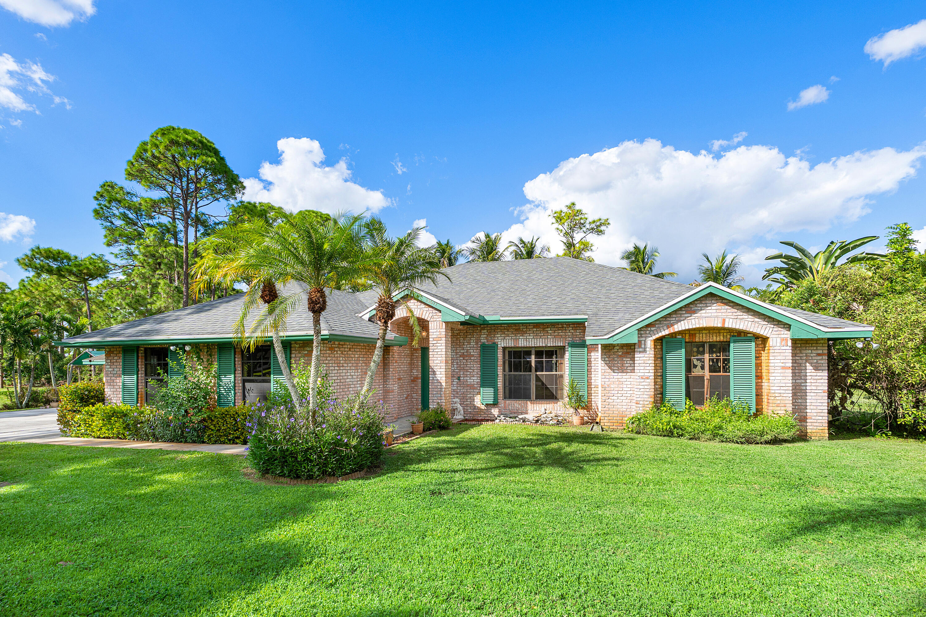 Single-story brick exterior featuring a multi-gabled roofline, green shutters, arched window accents, and manicured landscaping Single-story brick exterior featuring a multi-gabled roofline, green shutters, arched window accents, and manicured landscaping