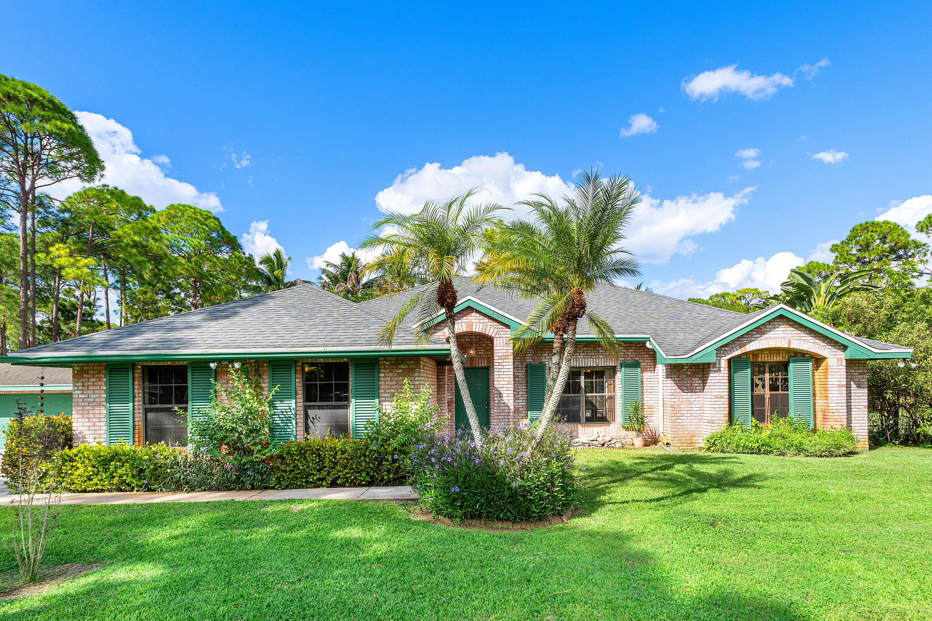 Single-story brick exterior featuring a shingled hip roof, decorative shutters, and an arched entryway