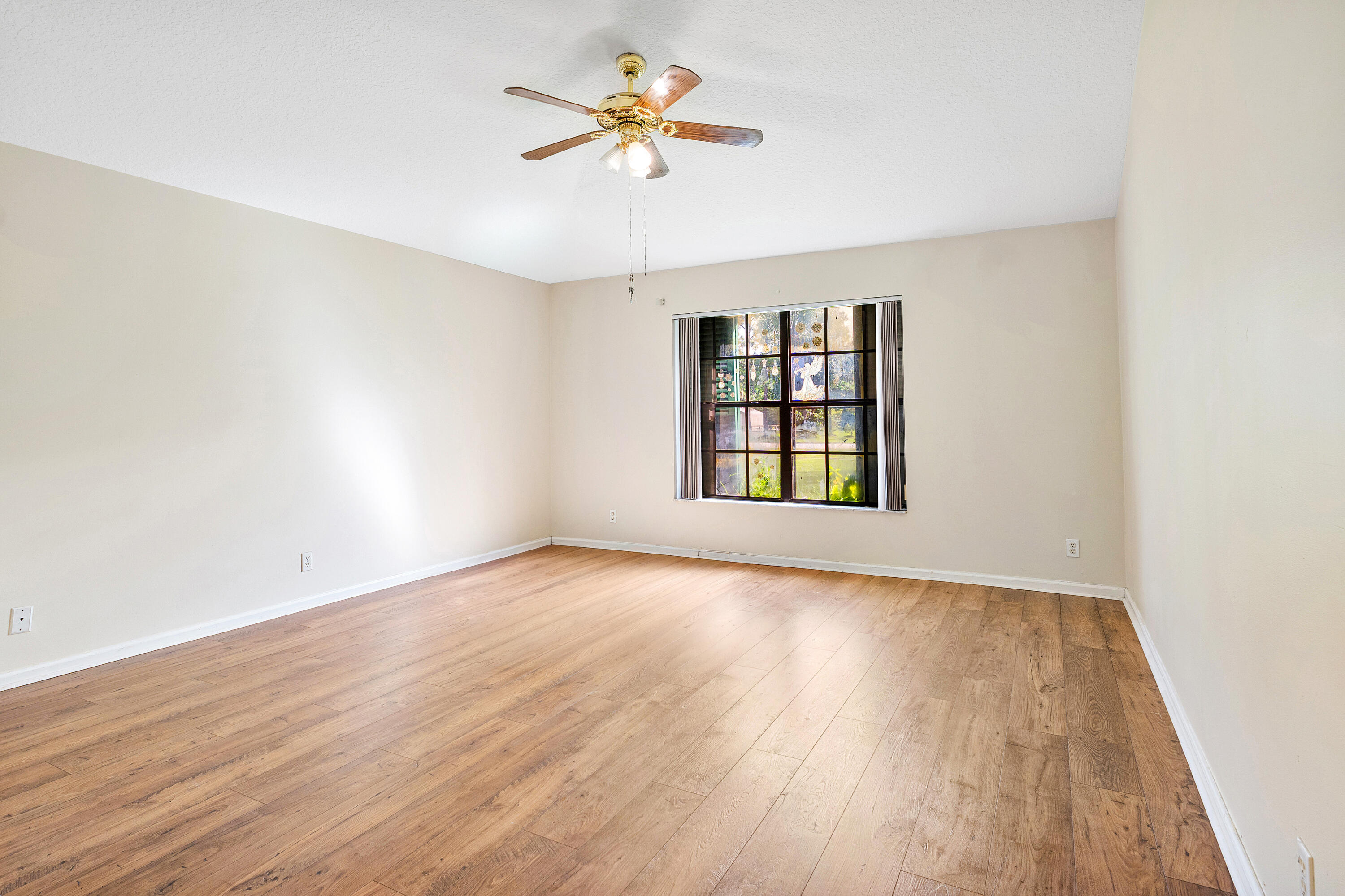 Primary bedroom ensuite number one featuring wood-finish flooring, a multi-pane window, and a ceiling fan with integrated lighting