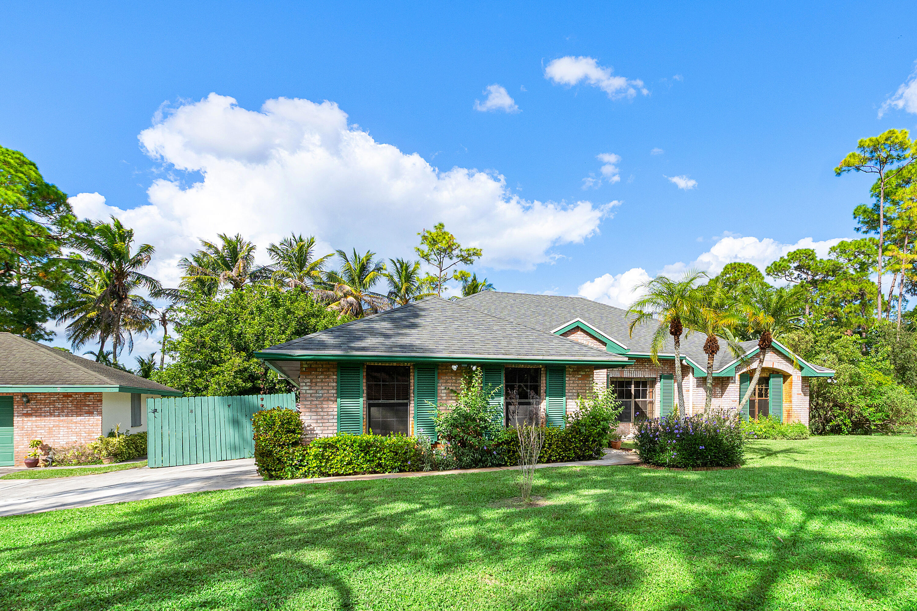 Single-story residence featuring a brick facade, architectural shingle roof, green shutter accents, and a concrete driveway Single-story residence featuring a brick facade, architectural shingle roof, green shutter accents, and a concrete driveway