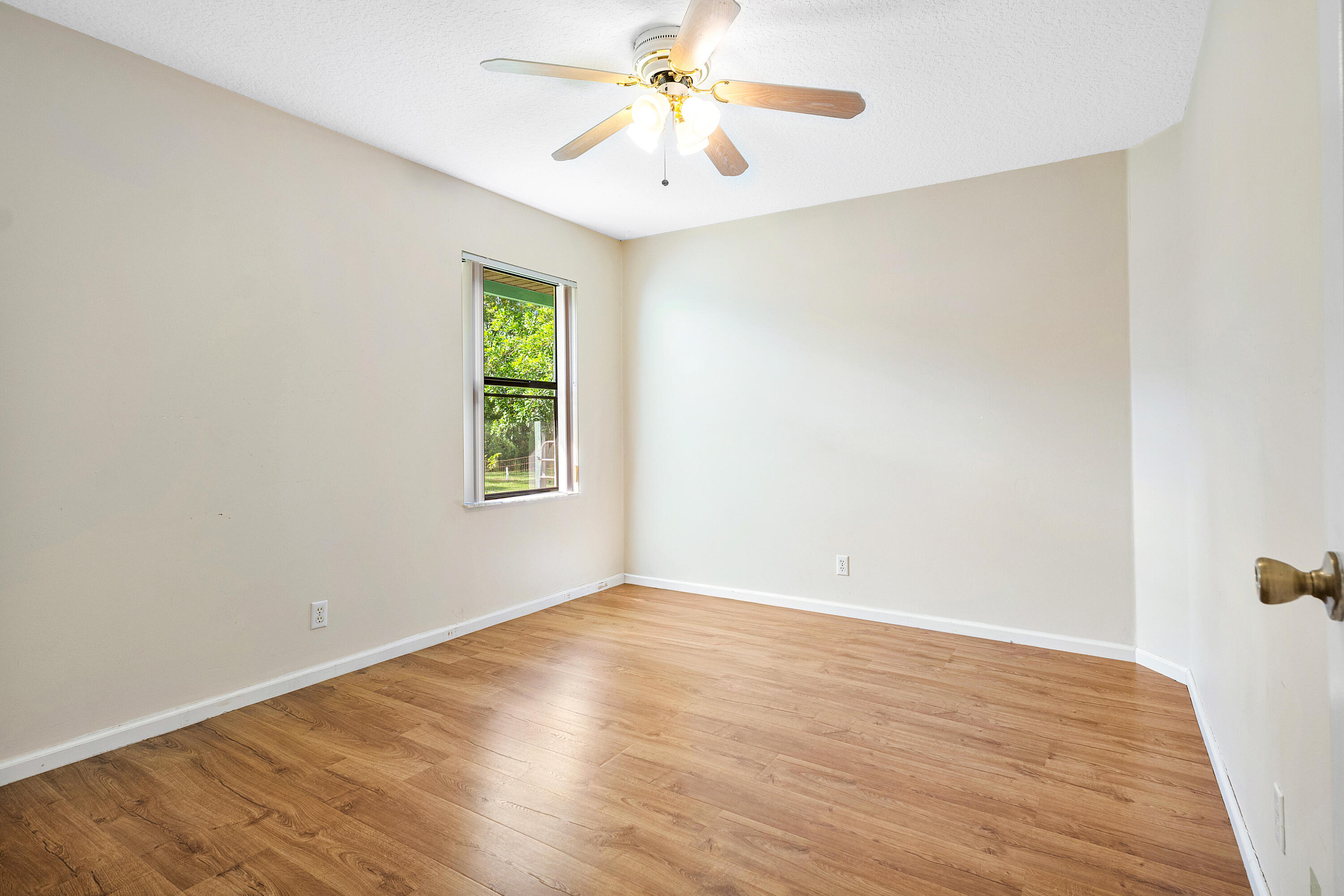Bedroom four featuring wood-finish flooring, a neutral wall palette, single-pane window, and a ceiling fan with integrated lighting