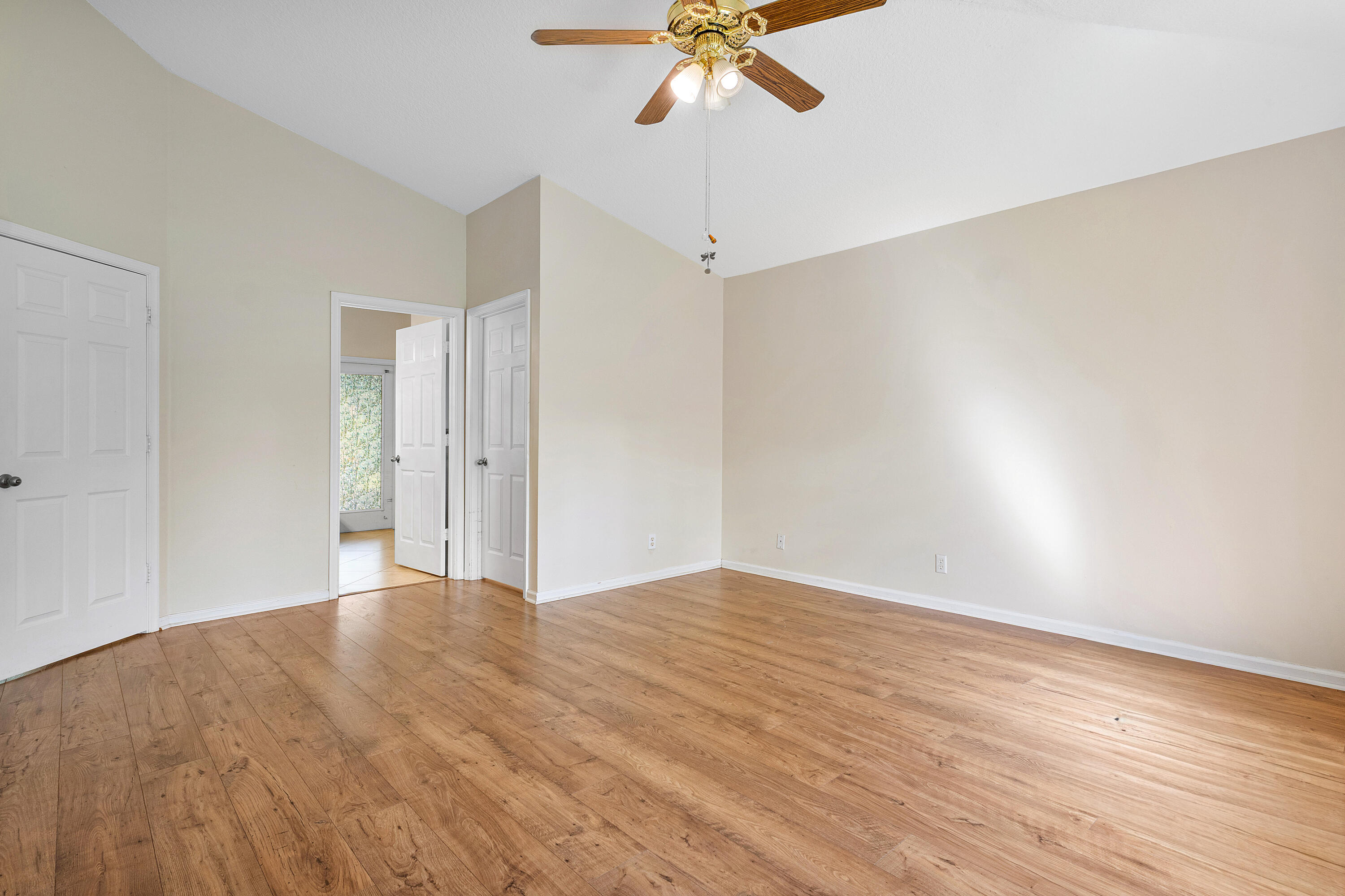 Primary bedroom ensuite number one boasts vaulted ceilings, wood-finish flooring, and a ceiling fan with integrated lighting