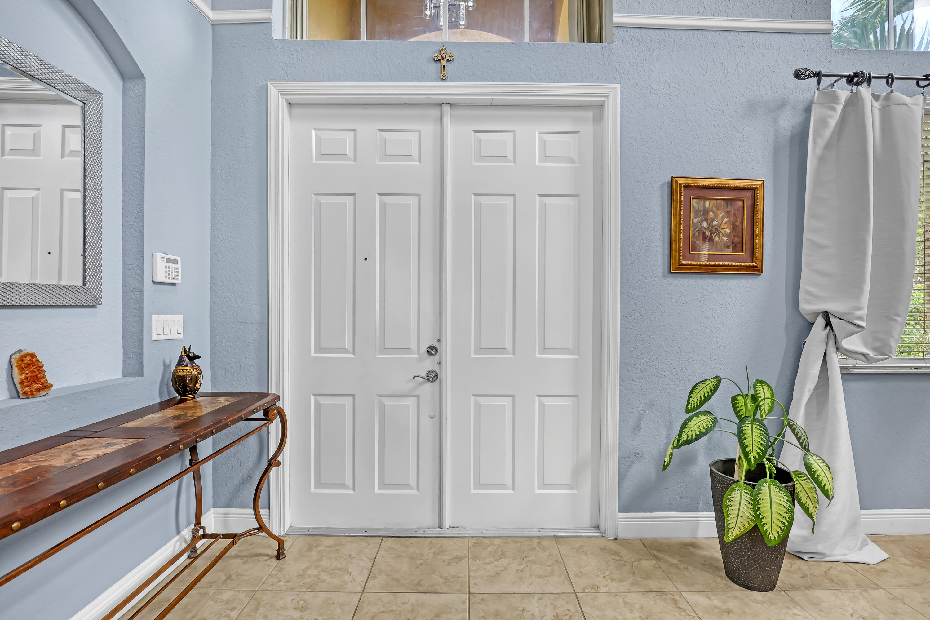 Double-door entry featuring paneled construction, high ceilings with a transom window, recessed wall niche, and tile flooring Double-door entry featuring paneled construction, high ceilings with a transom window, recessed wall niche, and tile flooring