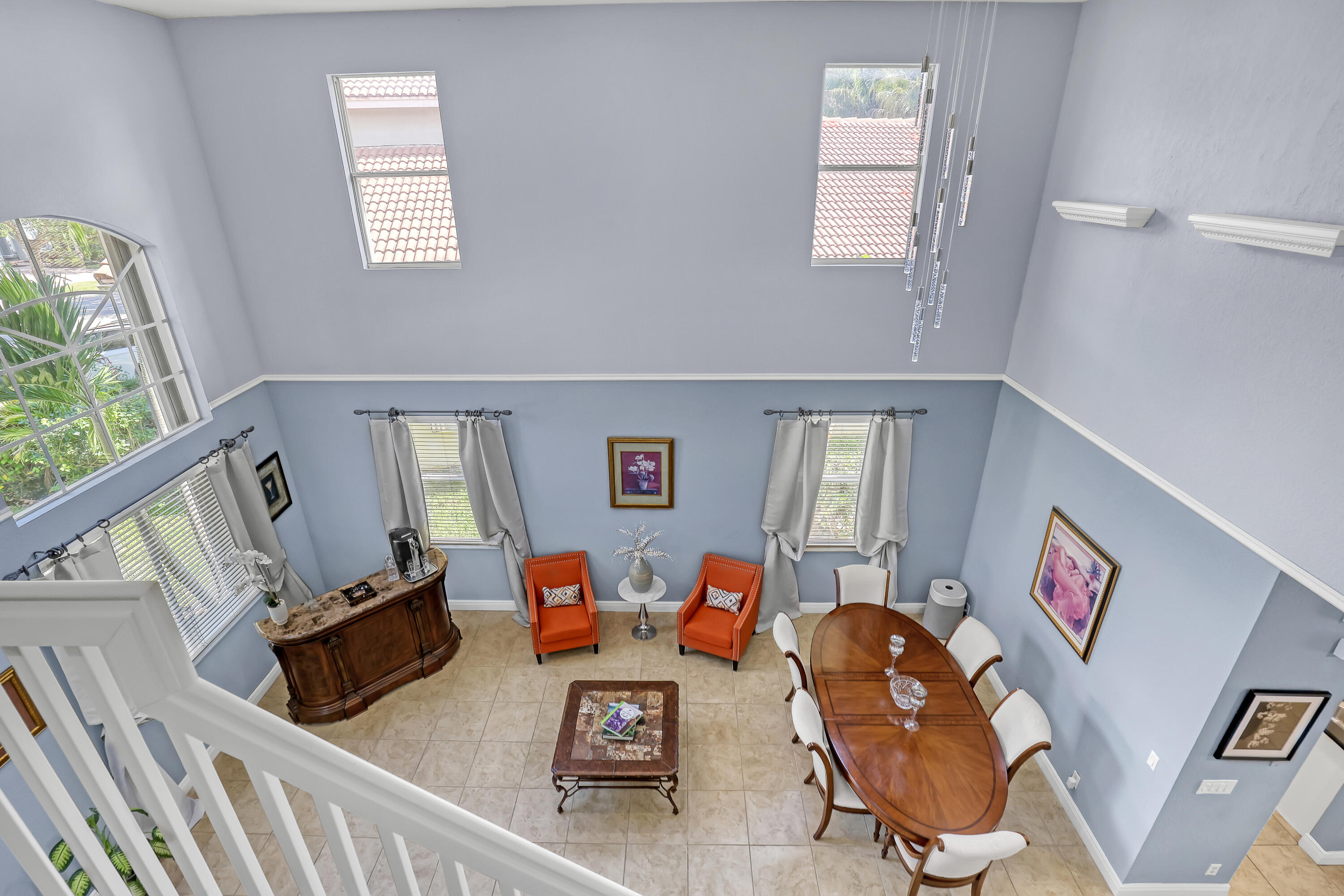 Double-height ceilings featuring multi-tiered windows, tile flooring, and a contemporary multi-pendant light fixture
