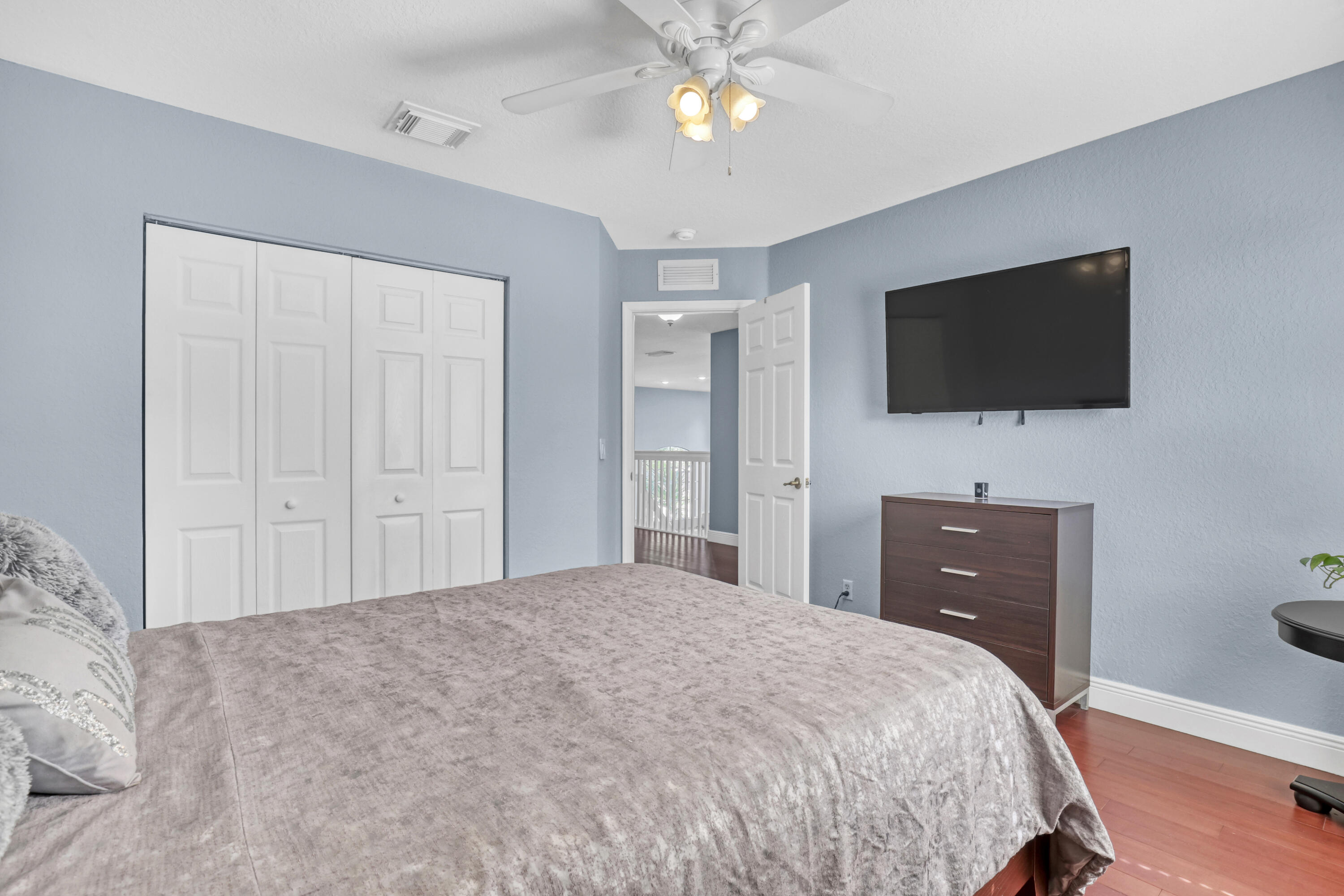 Room featuring wood-finish flooring, white bi-fold closet doors, a multi-bulb ceiling fan, and six-panel interior doors