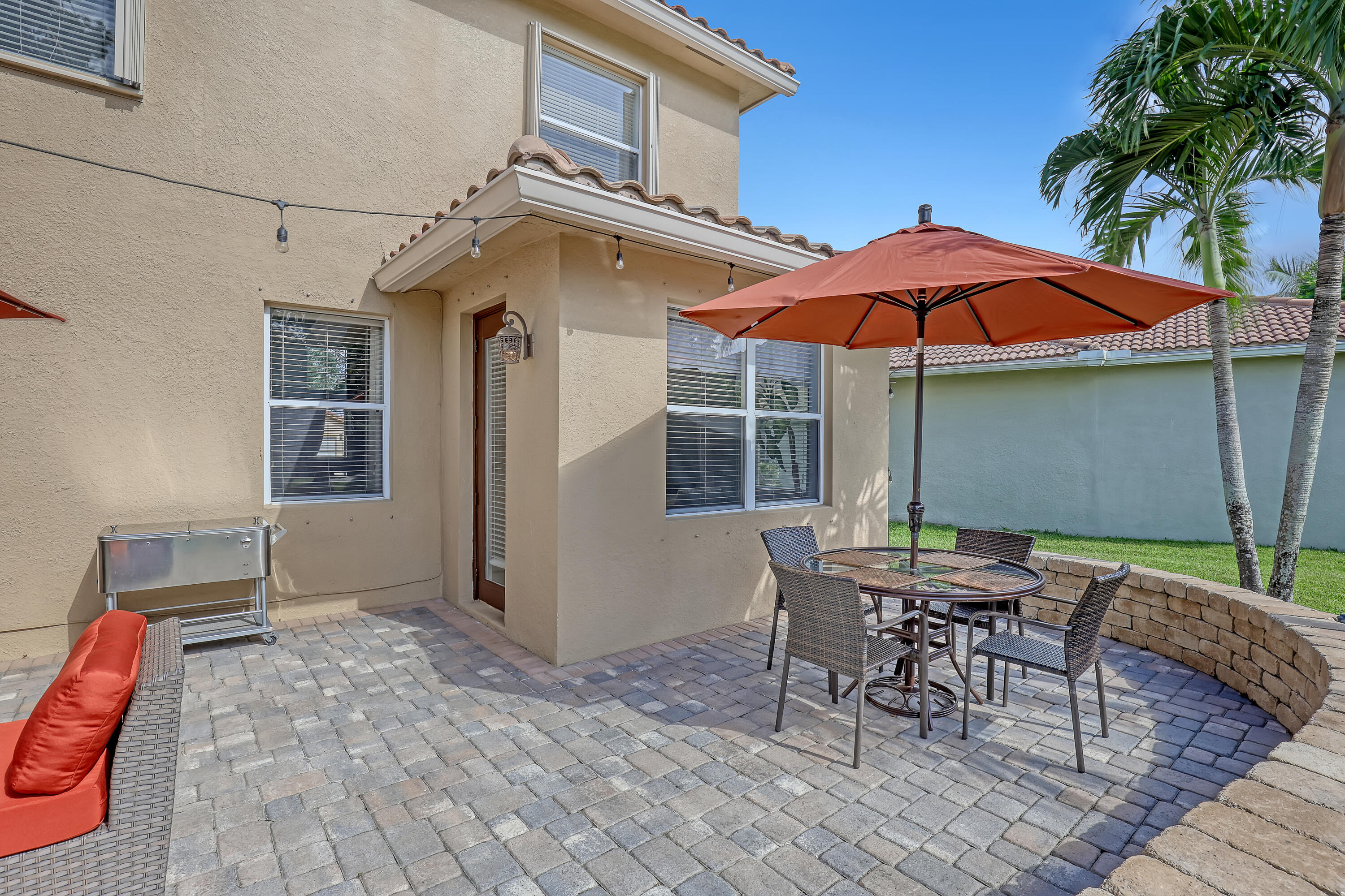 Stucco exterior featuring a paver patio, integrated segmental retaining wall, and exterior string lighting