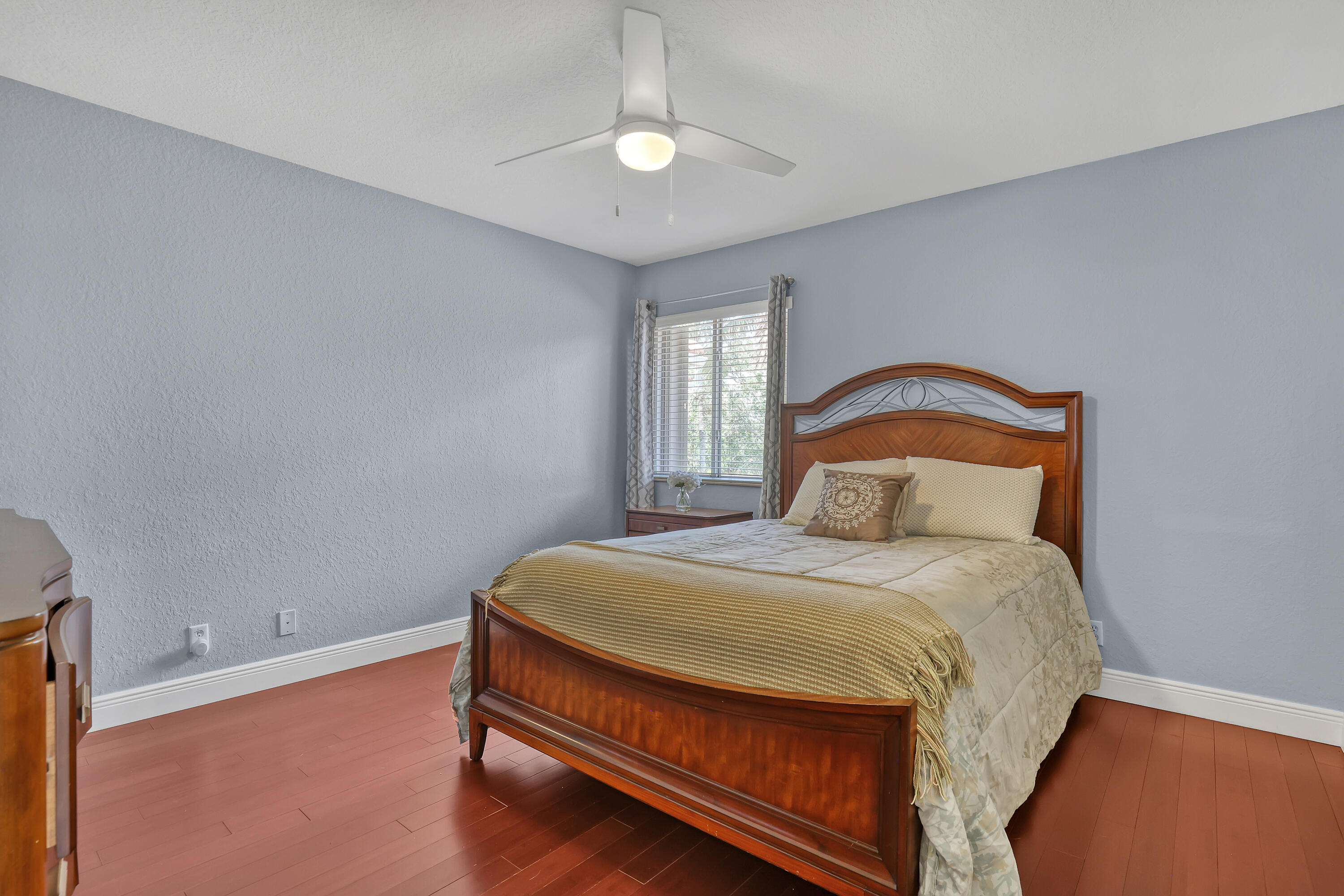 Room featuring wood-finish flooring, a white three-blade ceiling fan with integrated lighting, and a single-pane window