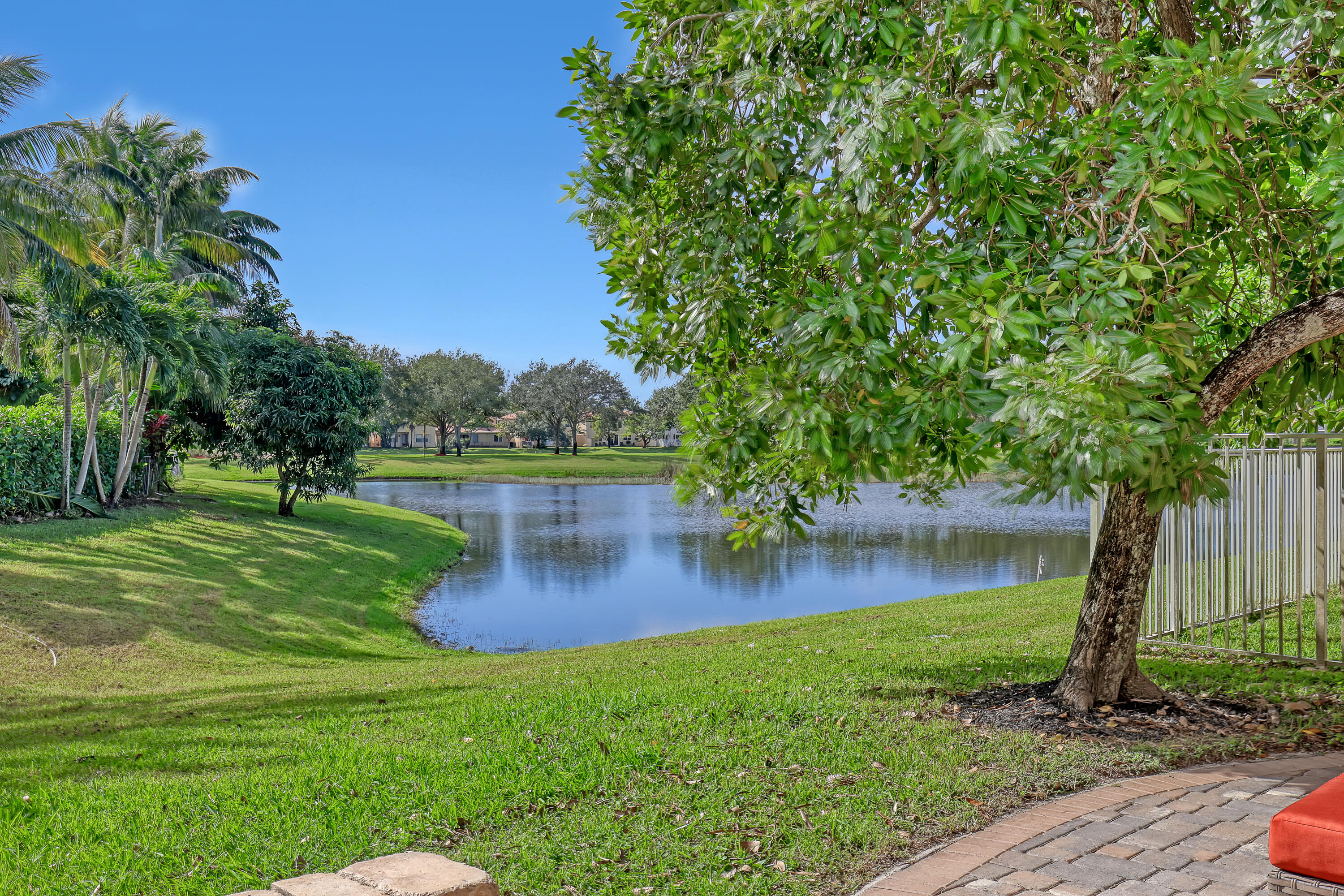 Paver patio, expansive green space, mature trees, and a water feature