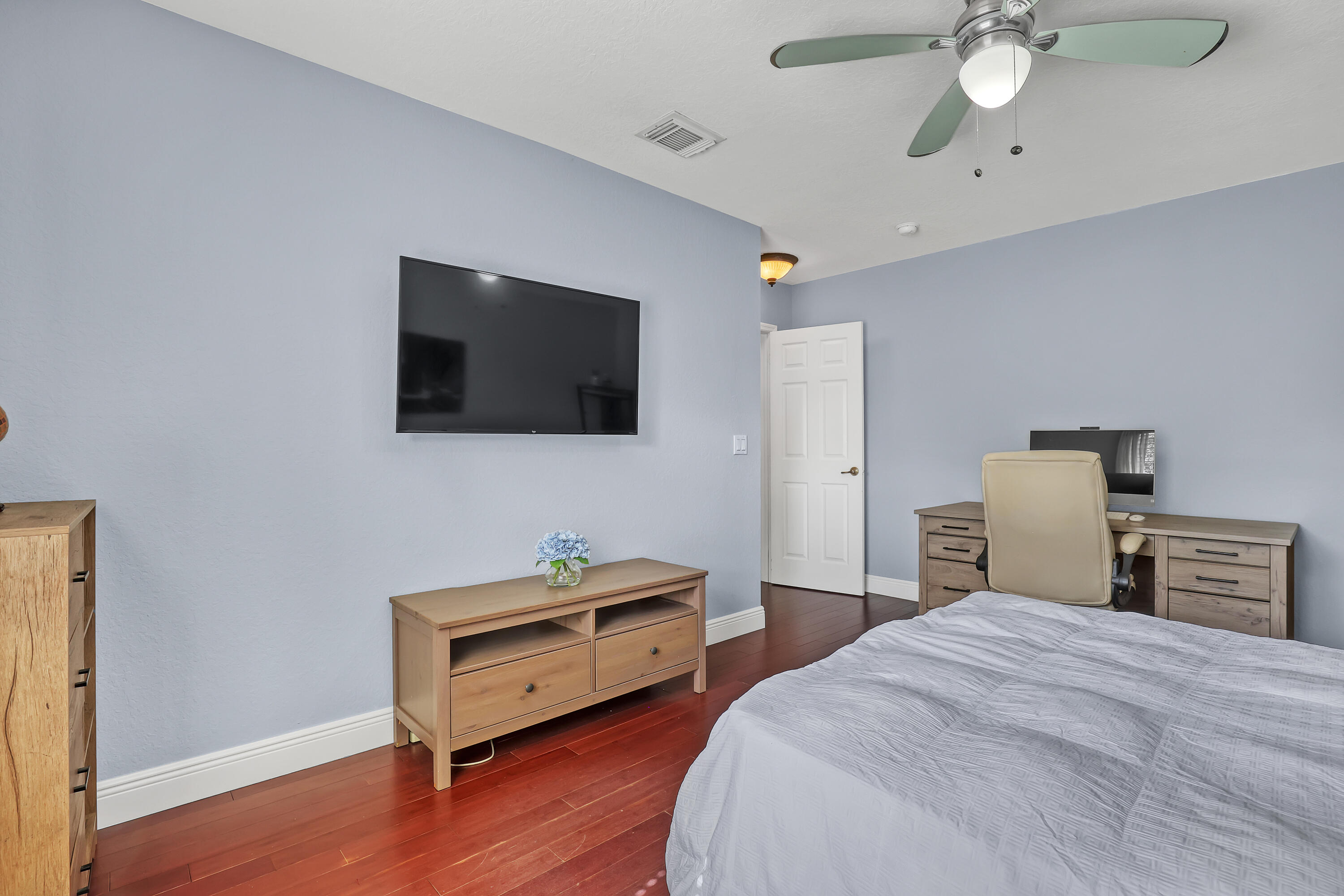 Wood-finish flooring, ceiling fan with integrated lighting, and a six-panel interior door