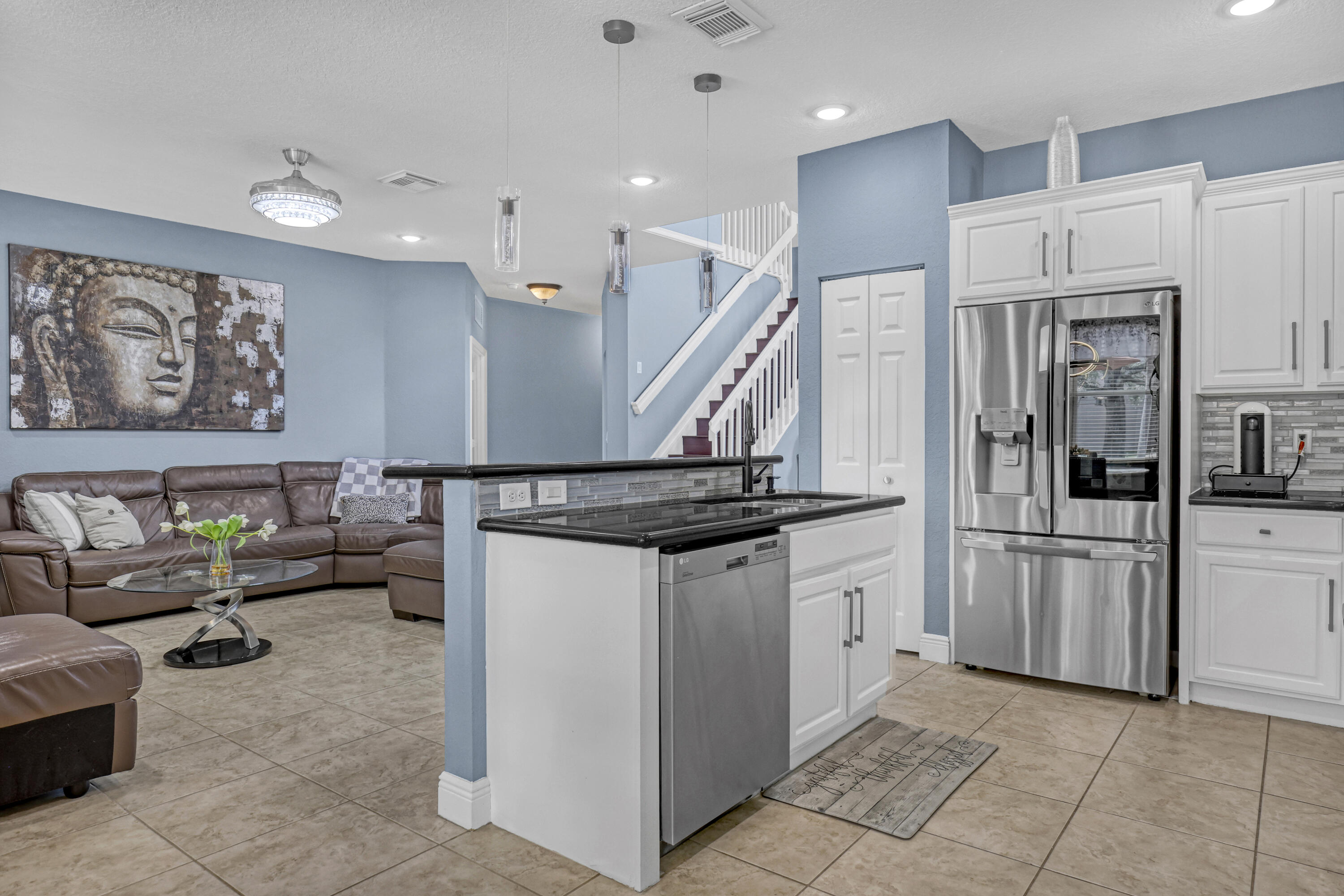 Kitchen island featuring a granite countertop, white shaker-style cabinetry, stainless steel appliances, tile flooring, and multi-pendant lighting Kitchen island featuring a granite countertop, white shaker-style cabinetry, stainless steel appliances, tile flooring, and multi-pendant lighting