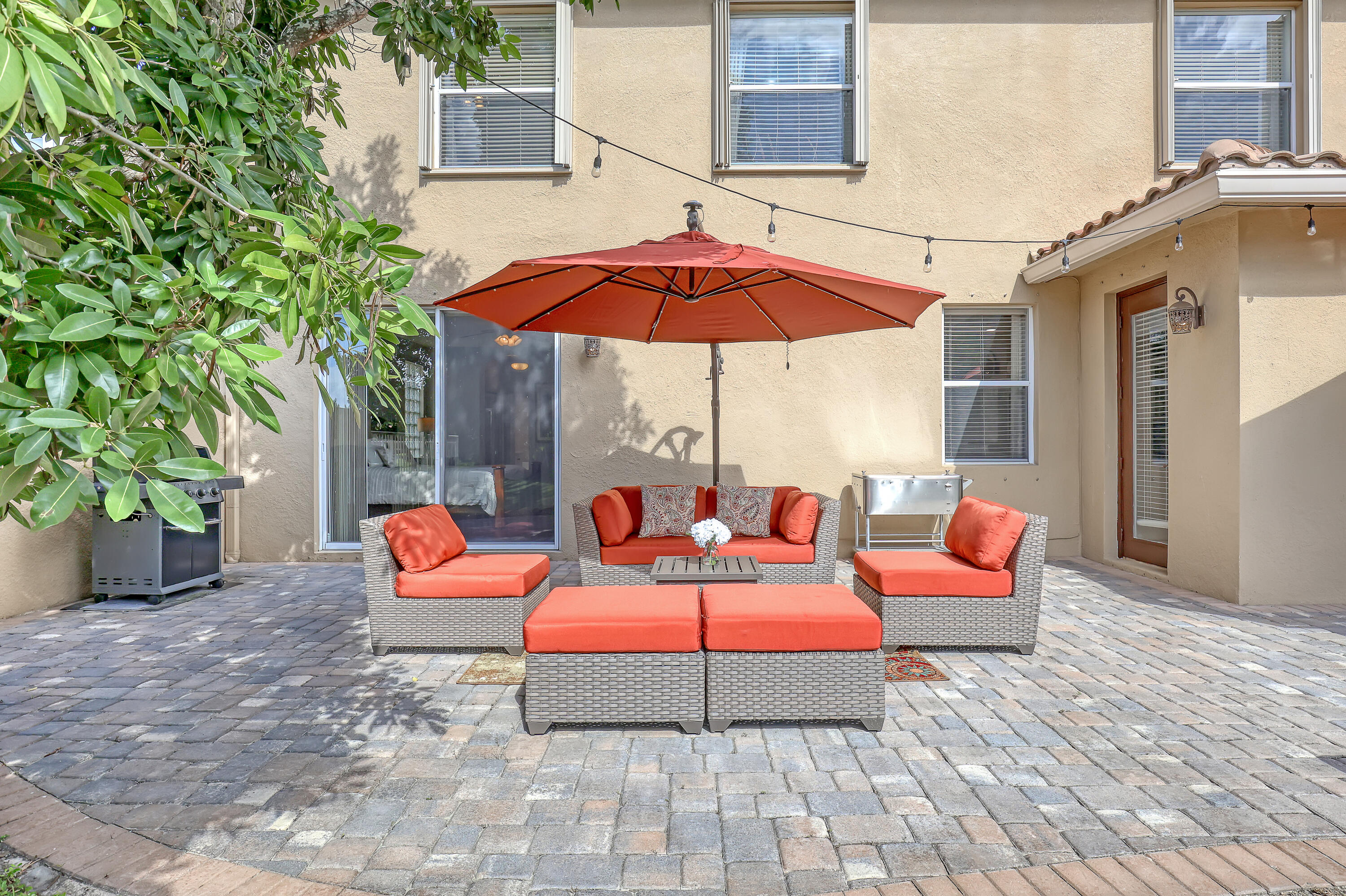 Stucco exterior patio featuring multi-tonal paver hardscaping, and dual entry points via a sliding glass door and a glass-paneled side door