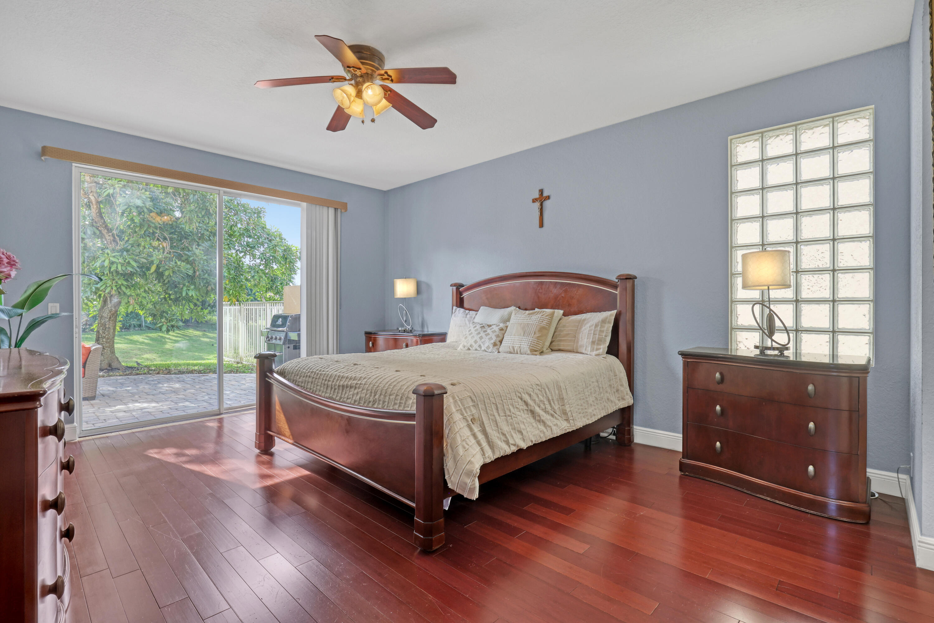 Wood-finish flooring, glass block window, sliding glass door, and ceiling fan with integrated lighting
