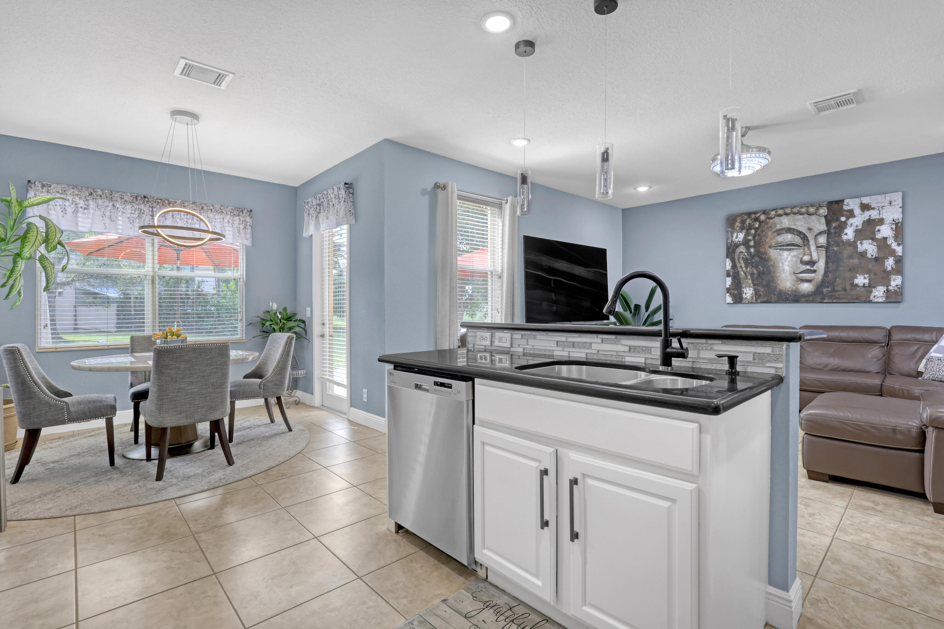 Kitchen island featuring white cabinetry, a granite countertop, and a matte black faucet, complemented by recessed lighting and neutral tile flooring