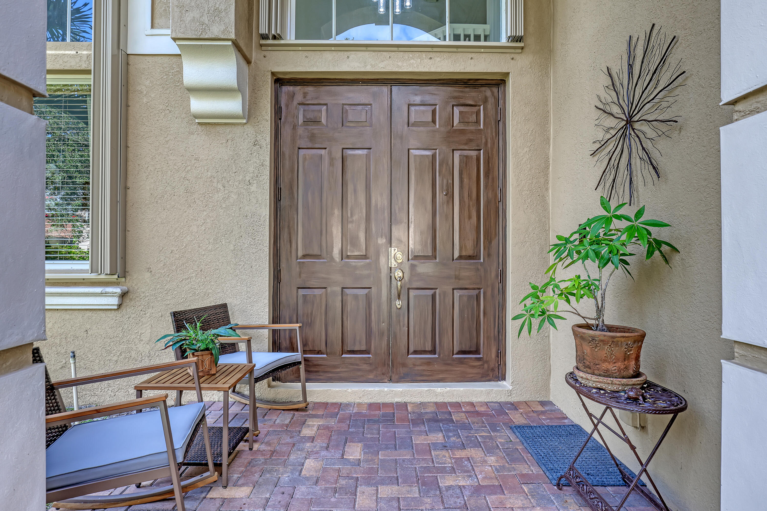 Double entry doors with a rich wood finish, multi-pane transom window, and paver stone porch Double entry doors with a rich wood finish, multi-pane transom window, and paver stone porch