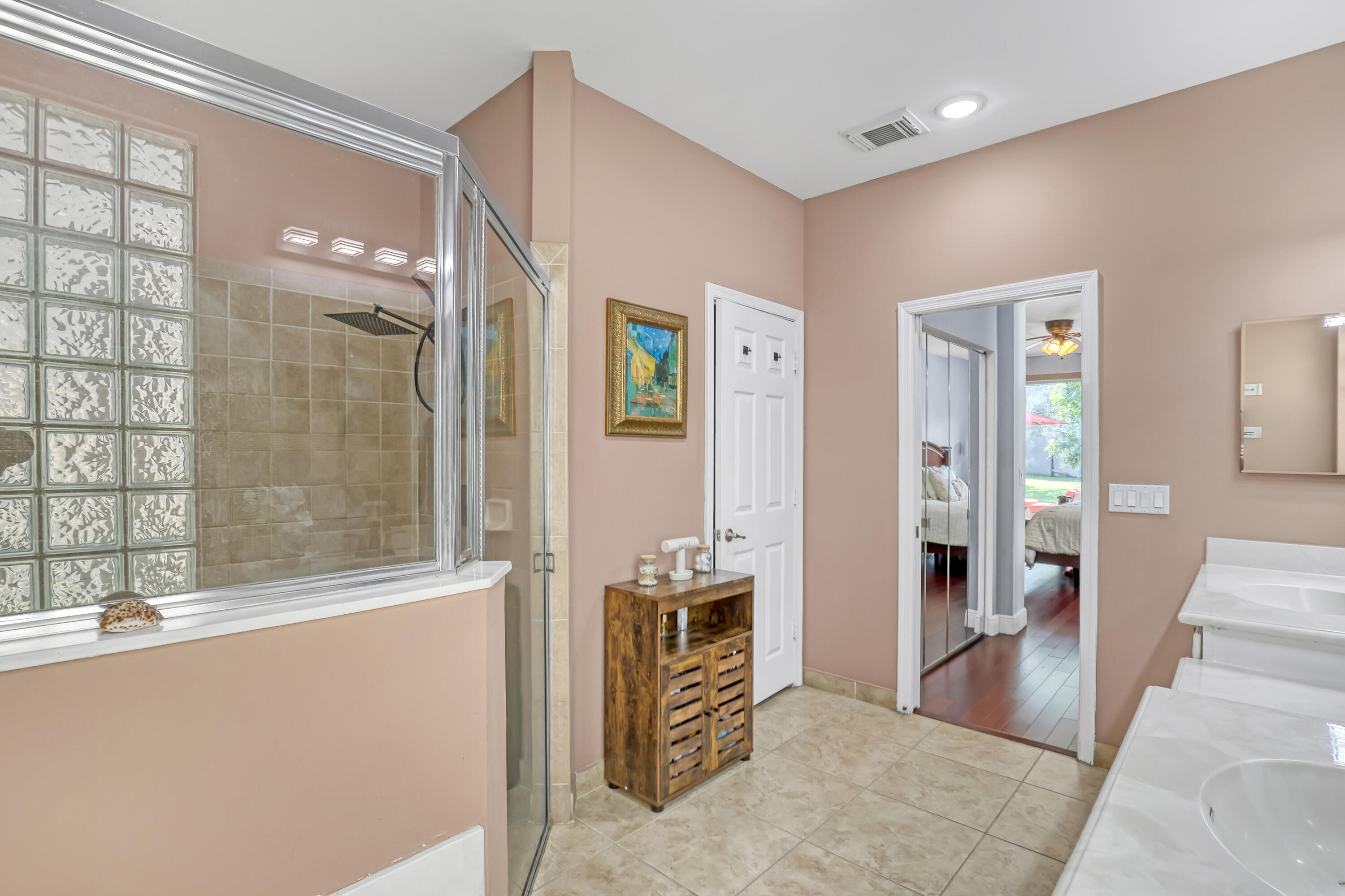 Shower enclosure and a rain-style shower head, tiled flooring, and dual vanity with integrated sinks