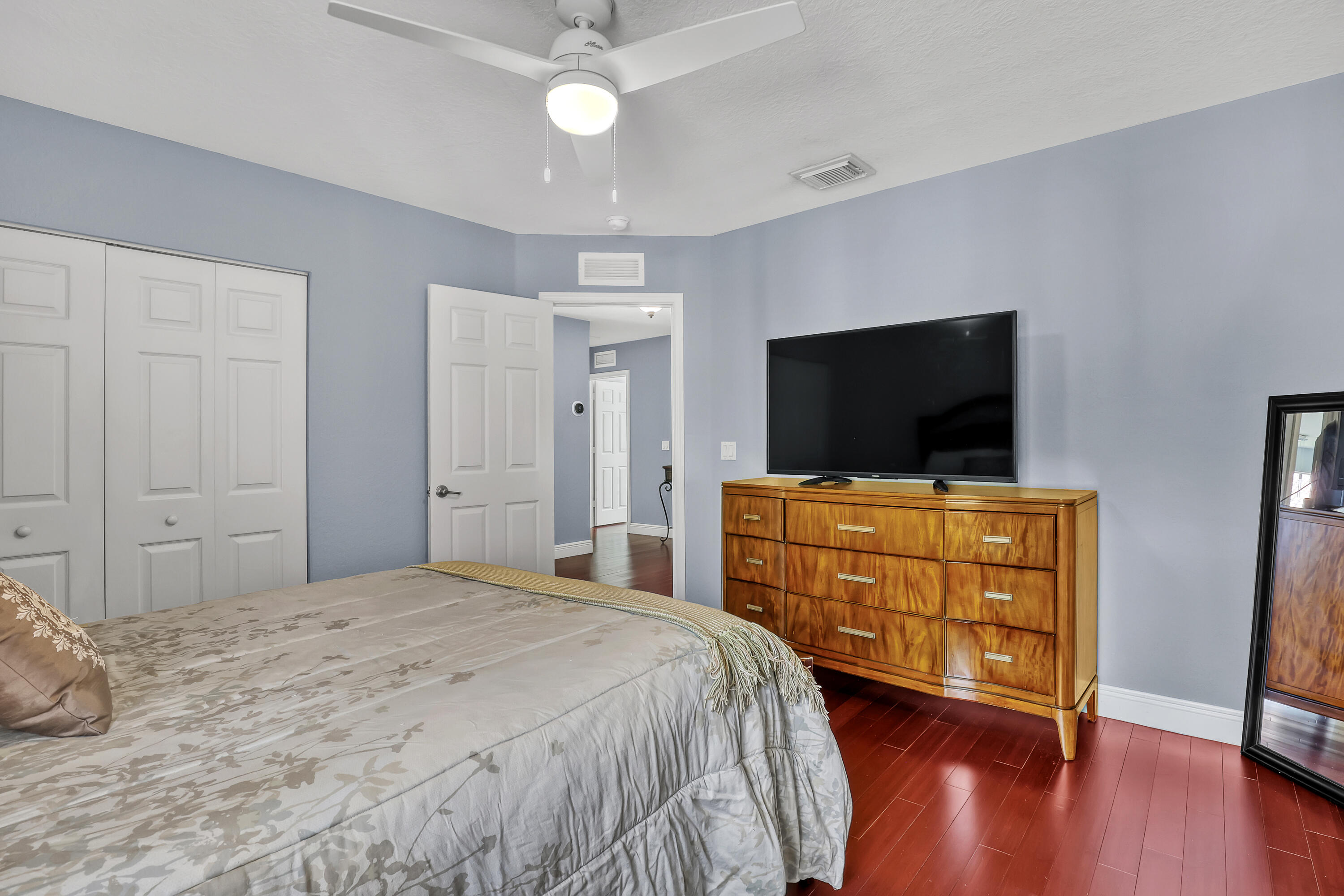 Room featuring wood-finish flooring, a ceiling fan with integrated lighting, and a dual-panel closet