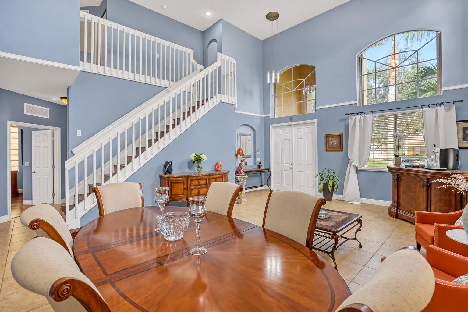 High-ceiling living area featuring tile flooring, expansive arched windows, crisp wall molding, and recessed lighting High-ceiling living area featuring tile flooring, expansive arched windows, crisp wall molding, and recessed lighting