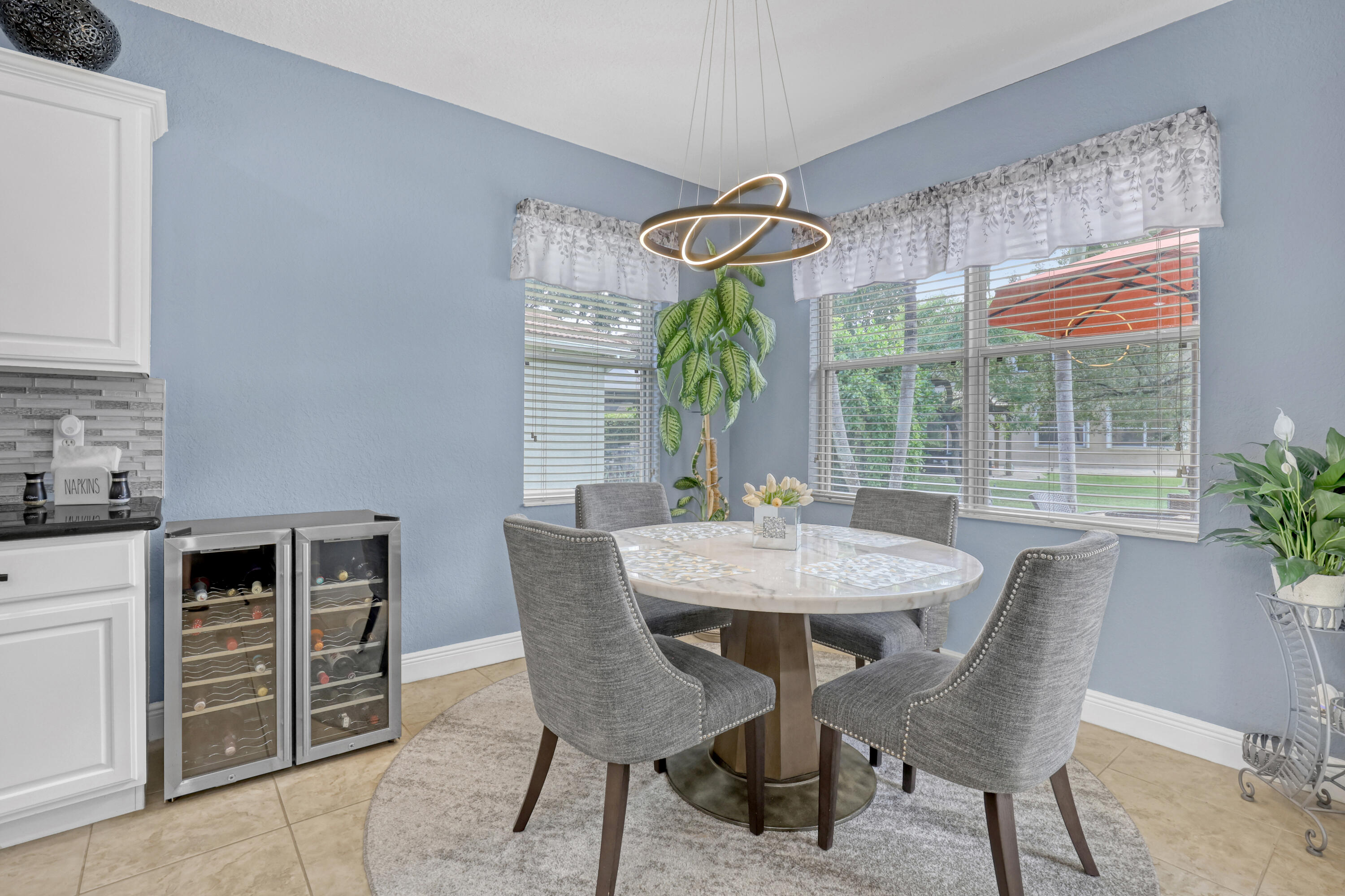 Modern circular LED chandelier, white cabinetry, tile flooring, and multi-pane windows