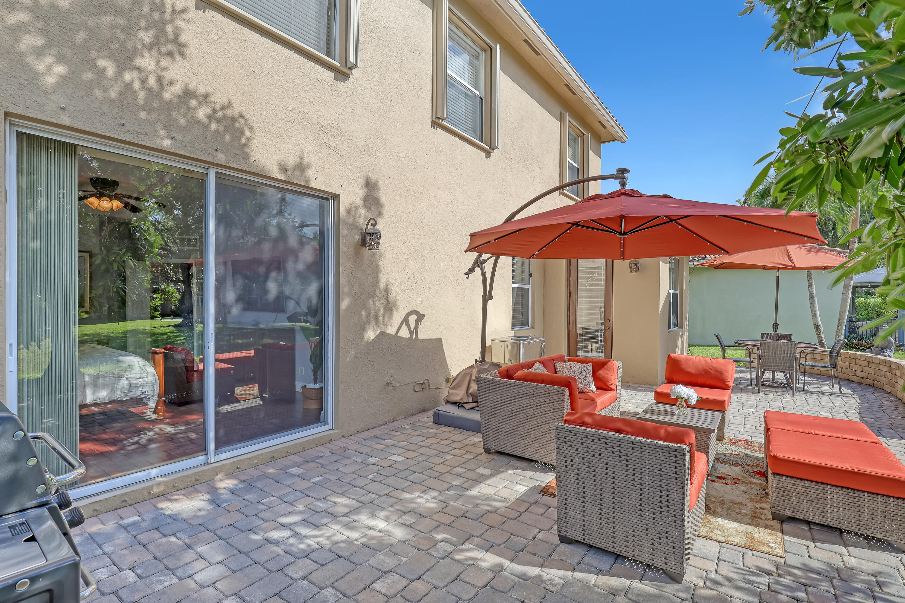 Stucco exterior featuring a sliding glass door, paved stone patio, and a low-profile stone retaining wall