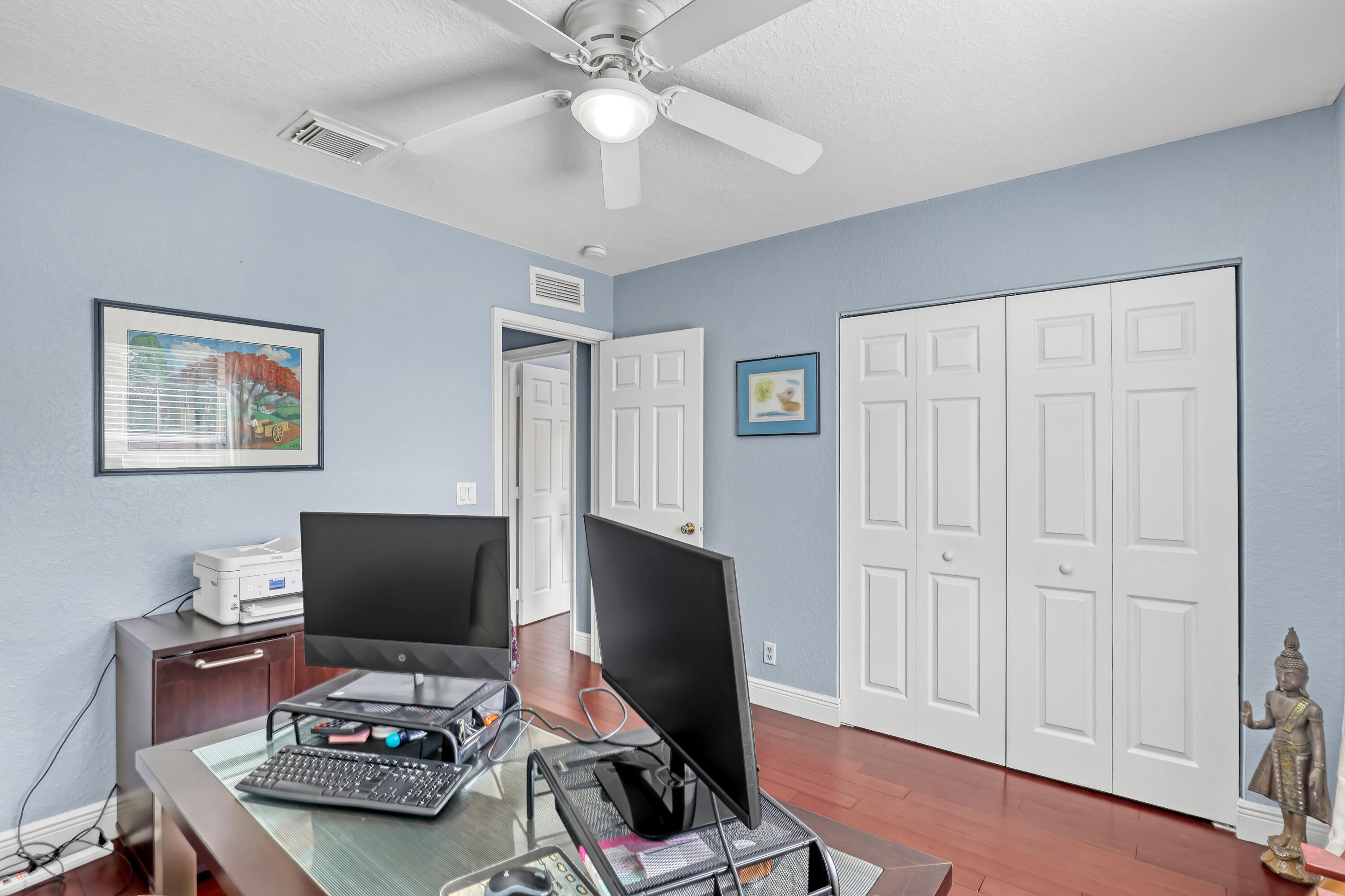 Room featuring wood-finish flooring, a white ceiling fan with integrated lighting, and a double-door closet with raised-panel detailing