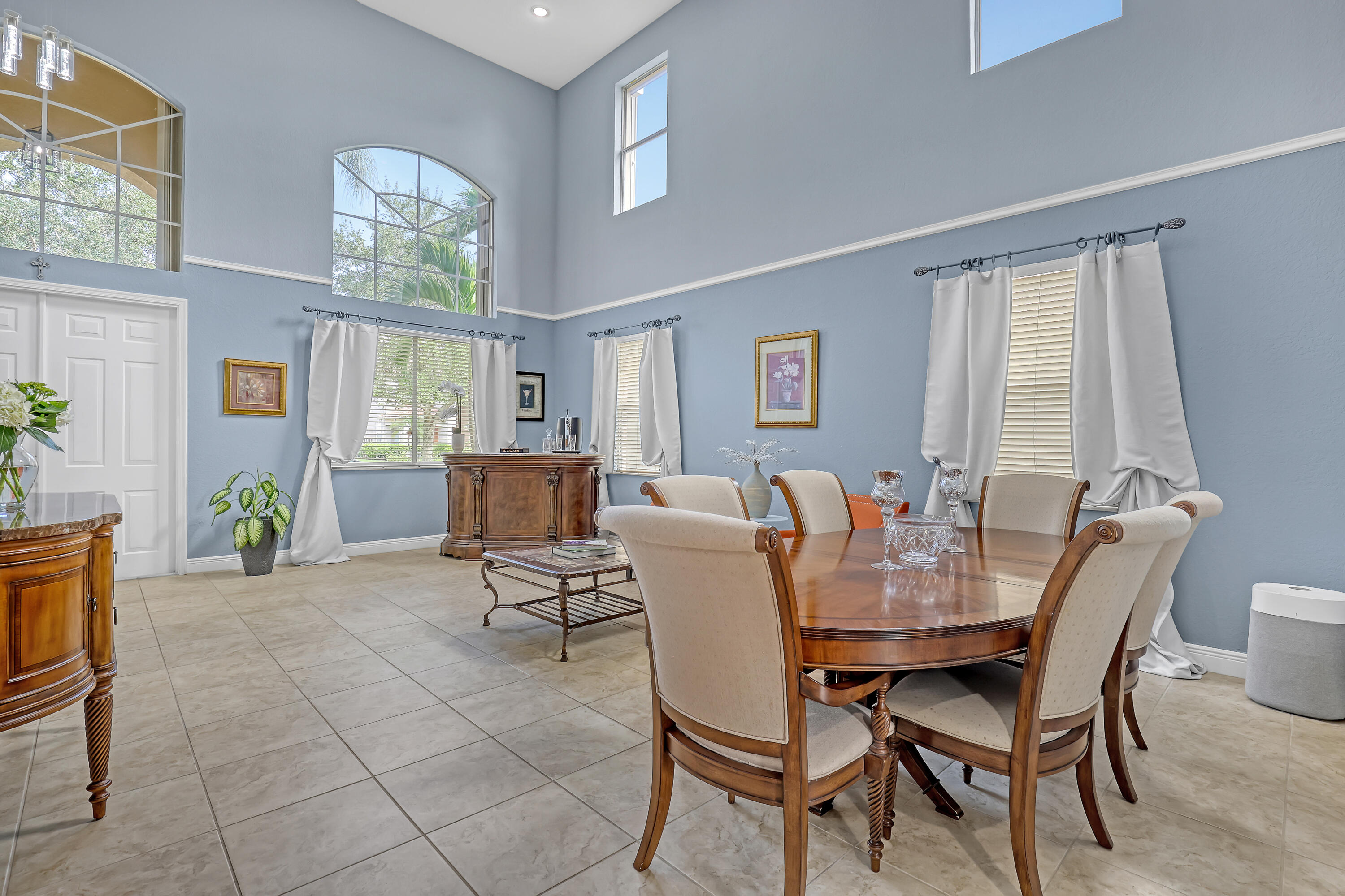 High-ceiling living area featuring tile flooring, expansive arched windows, crisp wall molding, and recessed lighting High-ceiling living area featuring tile flooring, expansive arched windows, crisp wall molding, and recessed lighting