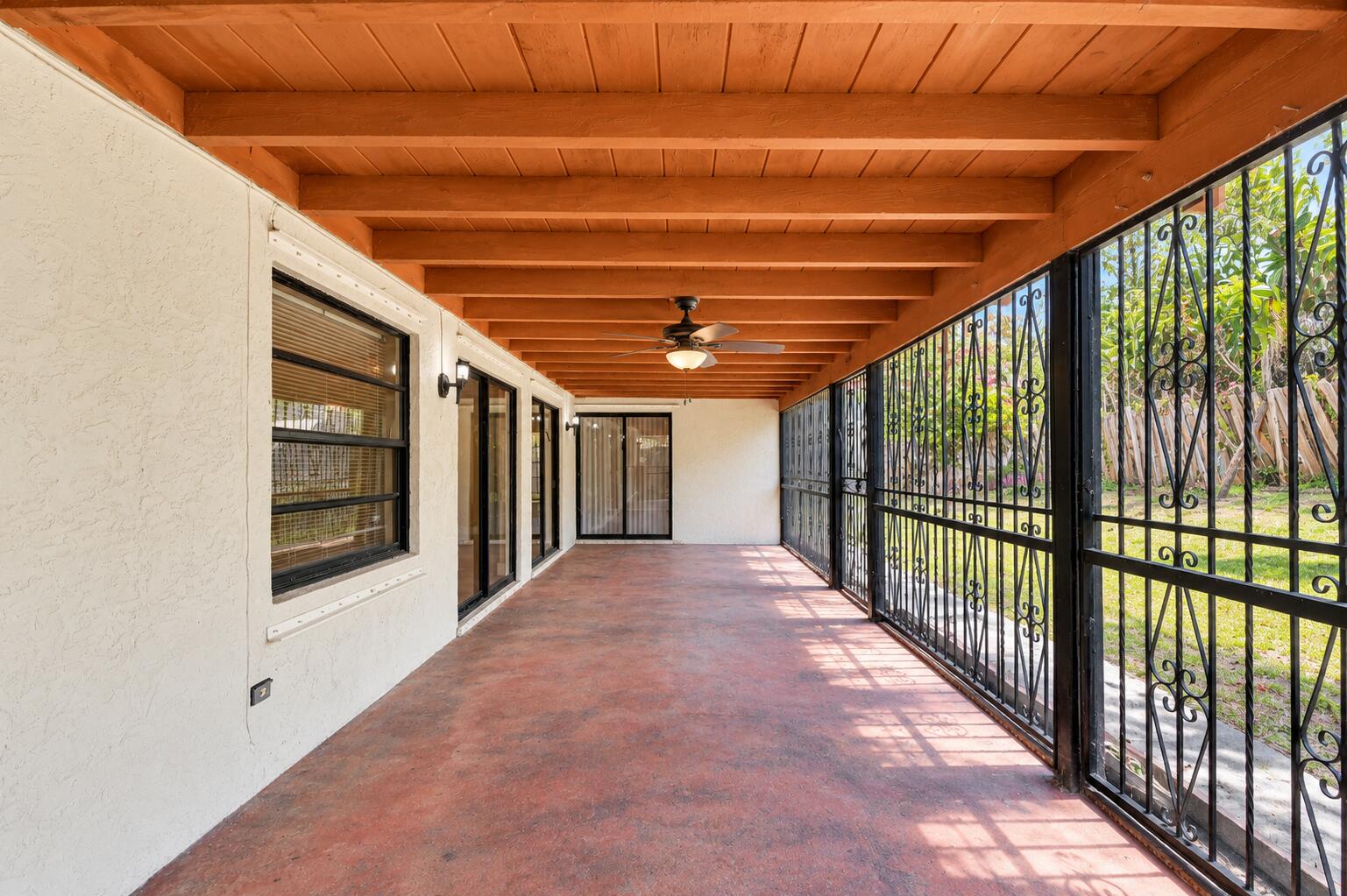 Expansive Covered Patio with Exposed Wood-Beam Ceiling, Ceiling Fan & Garden Views