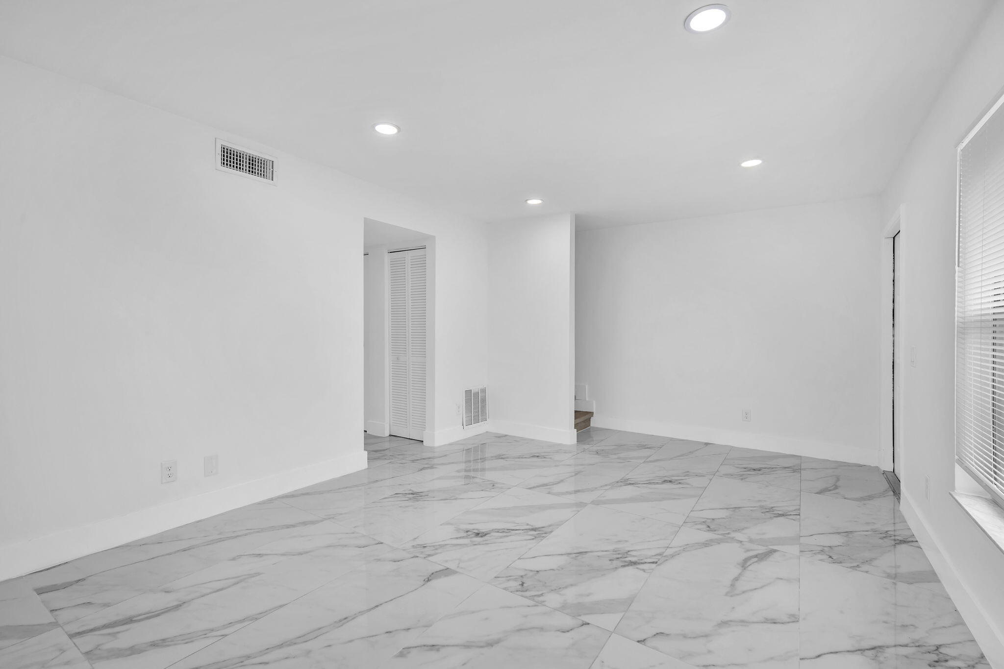 Large-format tile flooring with marble-patterned finish, recessed ceiling lighting, and crisp white wall finishes