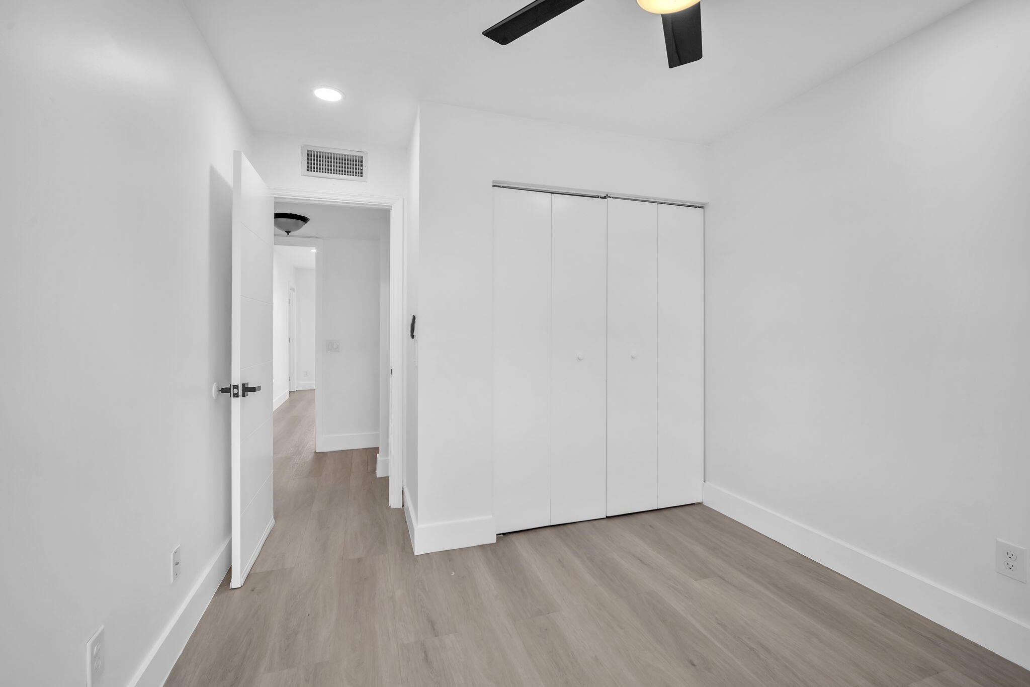 Room featuring wood-finish flooring, white bi-fold closet doors, recessed lighting, and a ceiling fan with integrated light