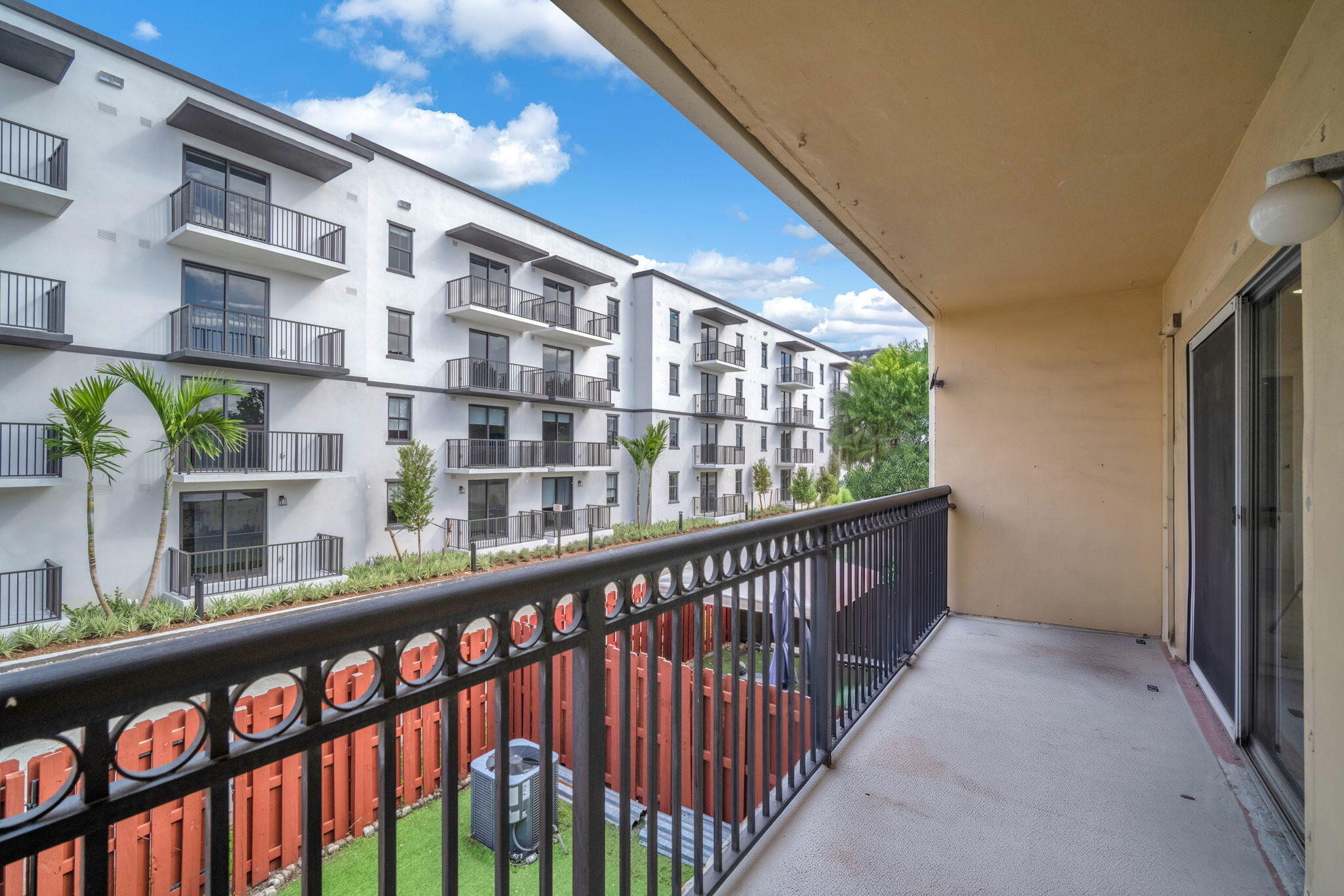 Covered balcony featuring metal railing, concrete flooring, and sliding glass door entry