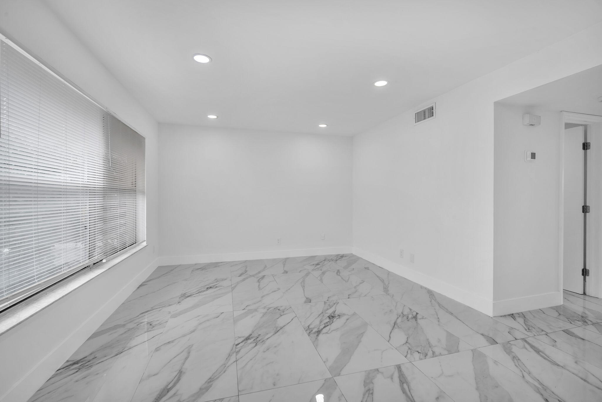 Large-format stone-look tile flooring, recessed ceiling lighting, and horizontal window blinds