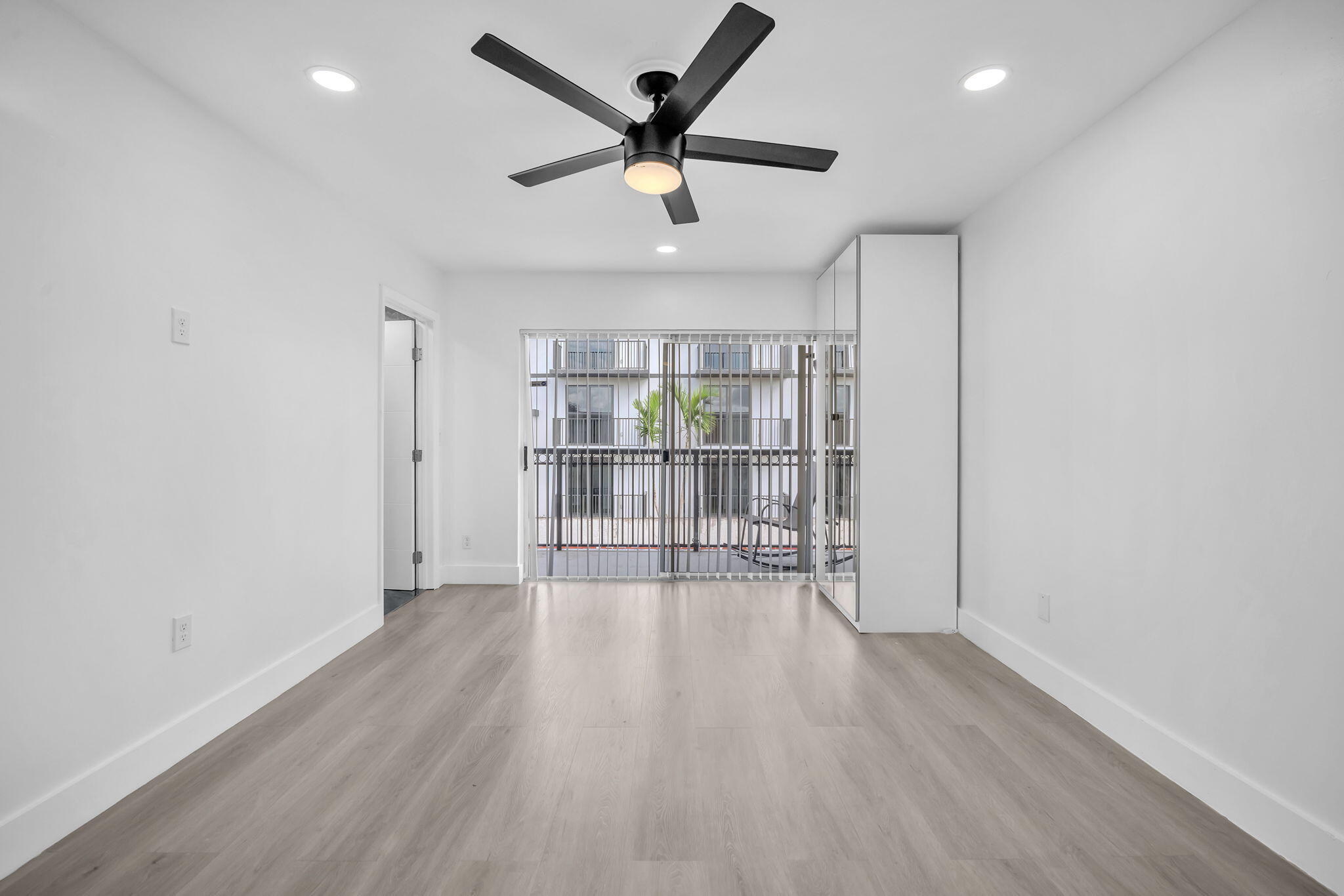 Wood-finish flooring, recessed lighting, ceiling fan with integrated light, built-in storage cabinetry, and sliding glass doors with exterior access