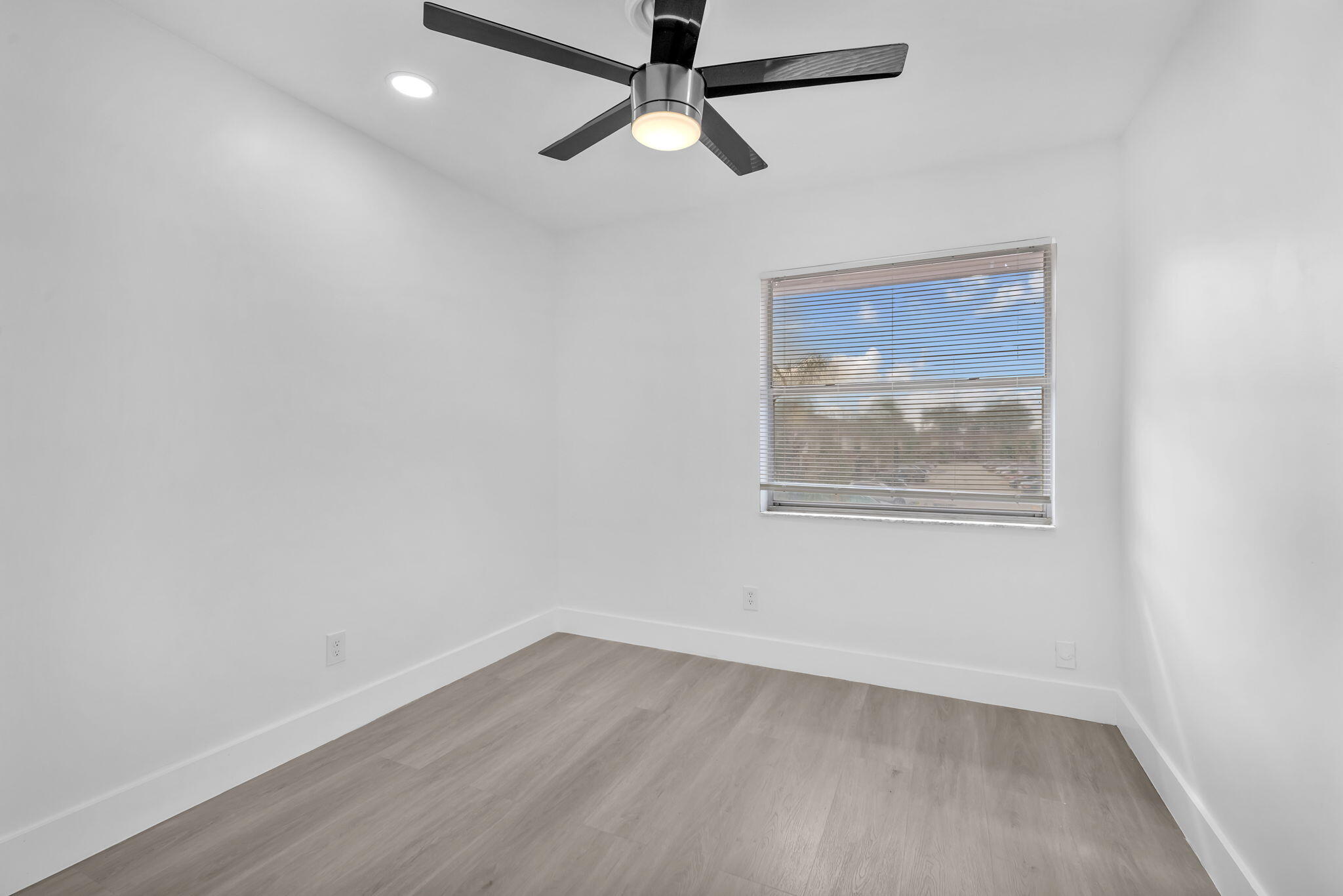 Room featuring wood-finish flooring, a contemporary ceiling fan with integrated lighting, recessed lighting, and a window with horizontal blinds