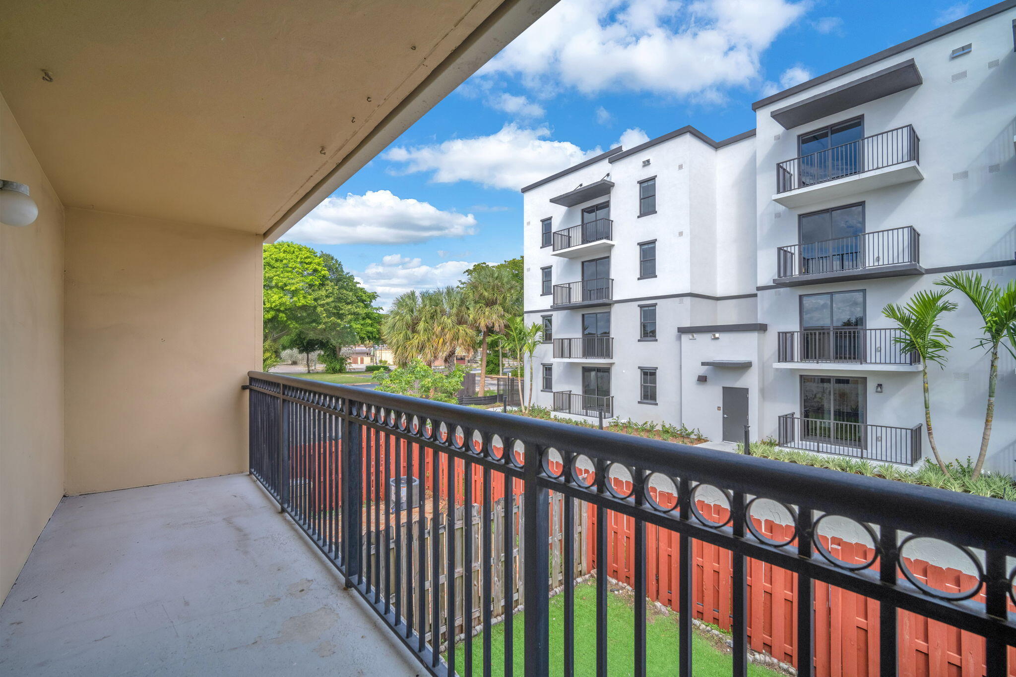 Covered balcony featuring black metal railings and concrete flooring