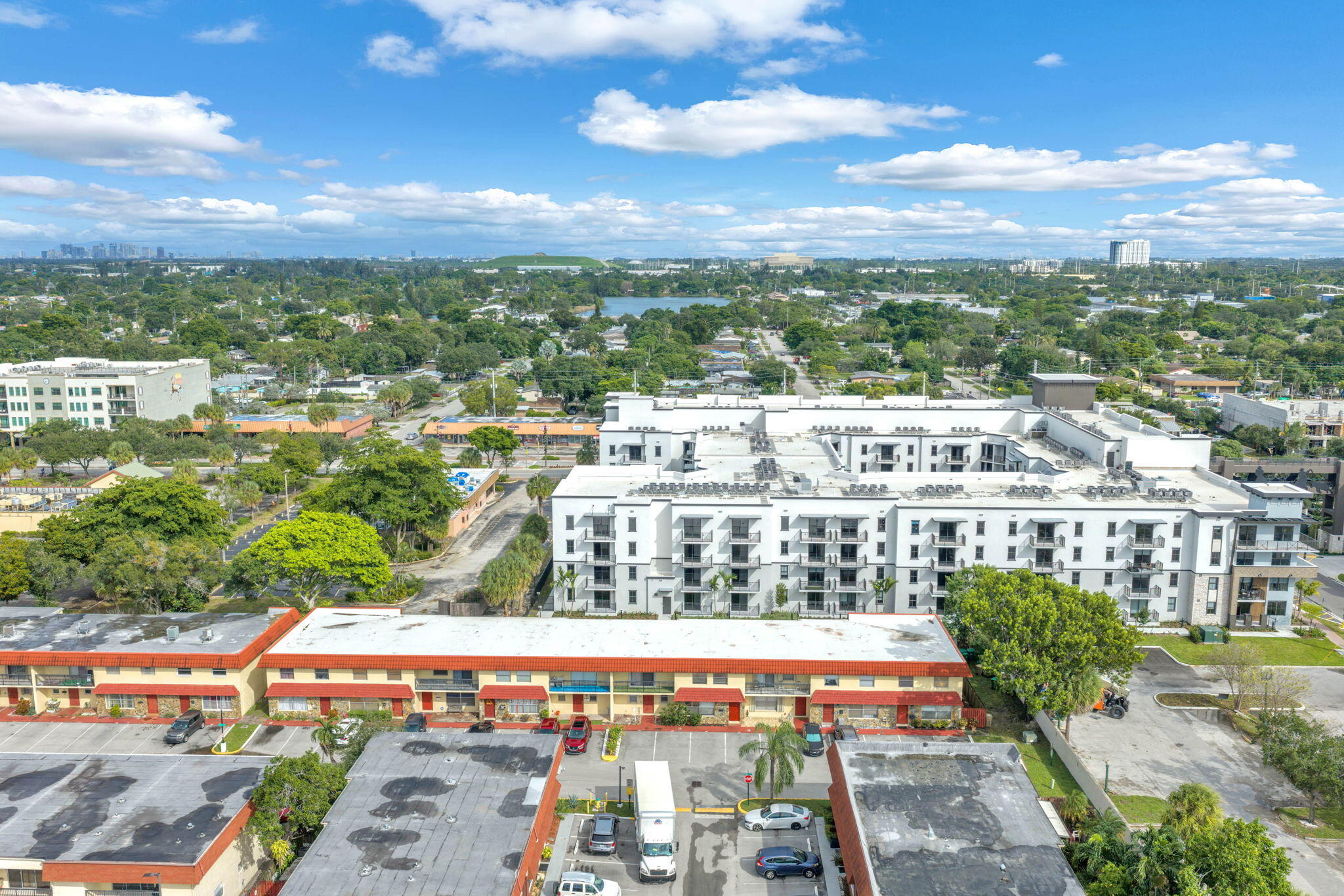 Aerial perspective featuring multi-story residential buildings, paved surface parking lots, and established landscaping with mature trees