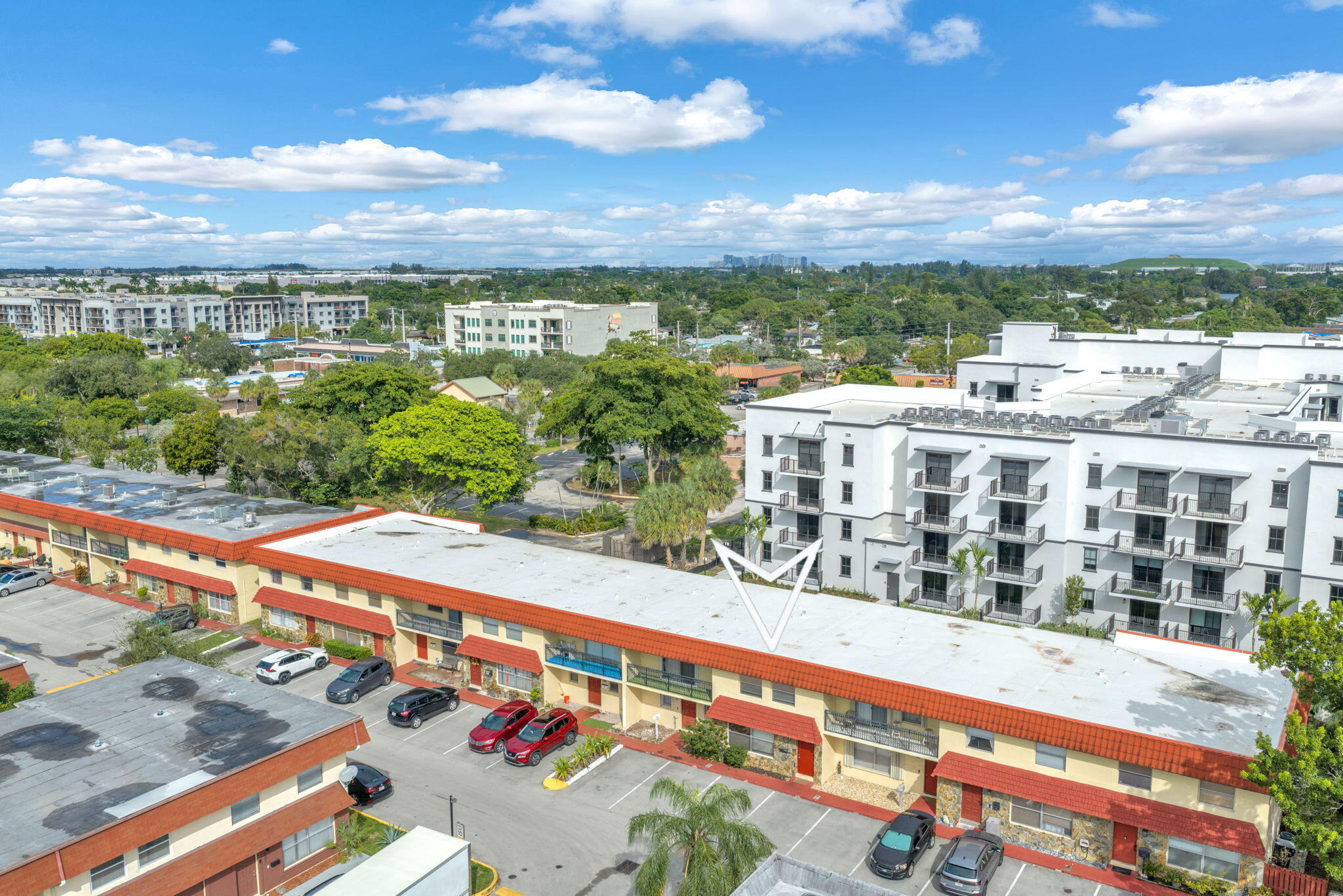 Exterior view of a multi-story residential building featuring a flat roof with tile accents, private balconies, and dedicated surface parking