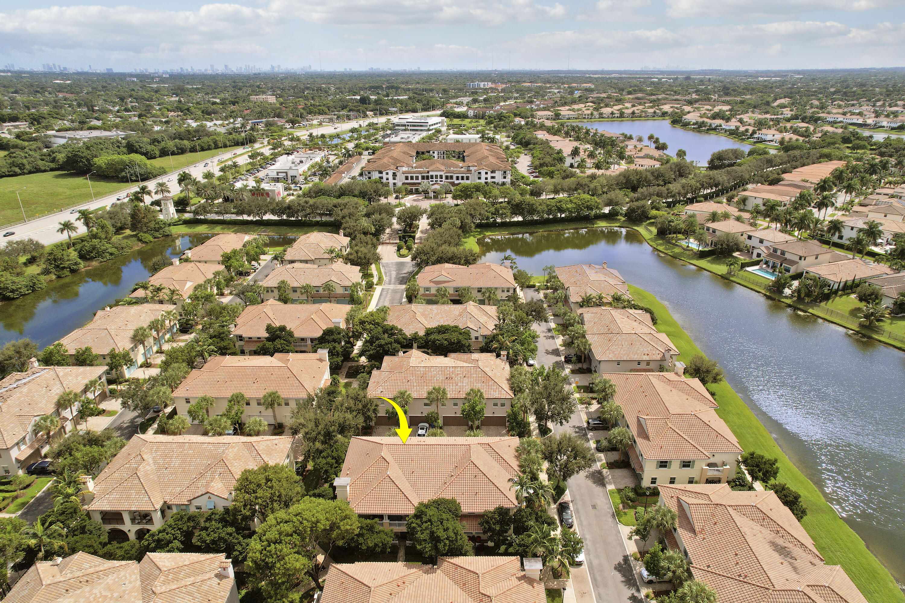 Aerial perspective of property featuring a tile roof, mature landscaping, and positioning within a water-front community