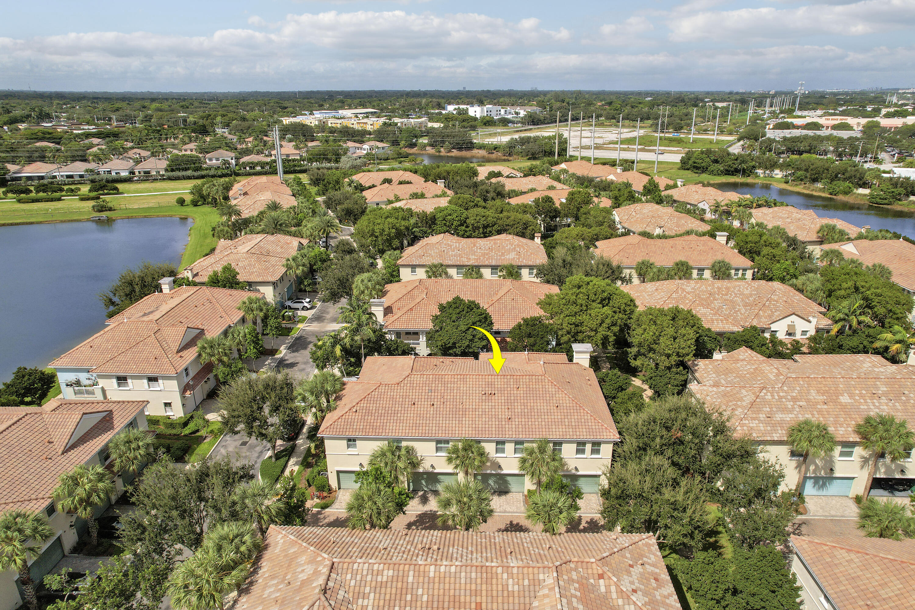 Aerial view featuring a multi-story residence with a tile roof, light-toned exterior finish, and multi-car garage configuration Aerial view featuring a multi-story residence with a tile roof, light-toned exterior finish, and multi-car garage configuration