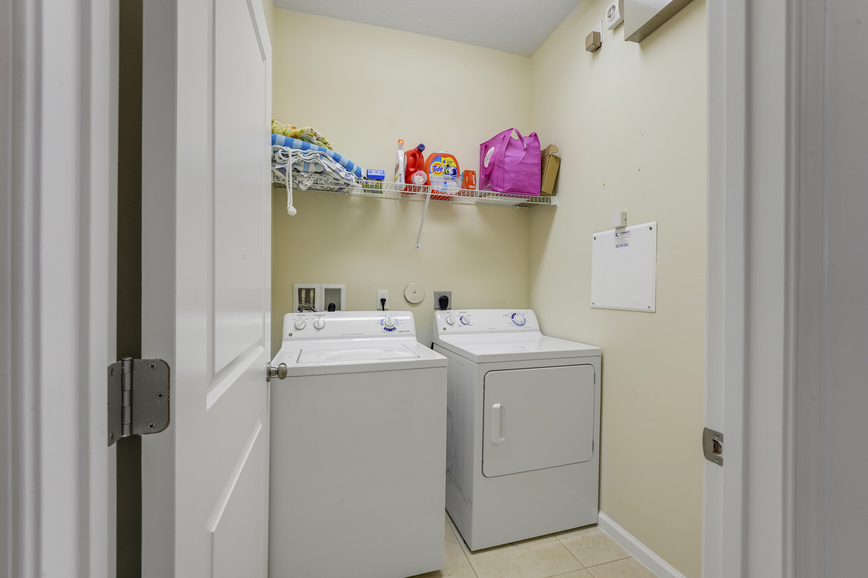 Laundry area featuring dedicated washer and dryer hookups, wire shelving, and neutral tile flooring