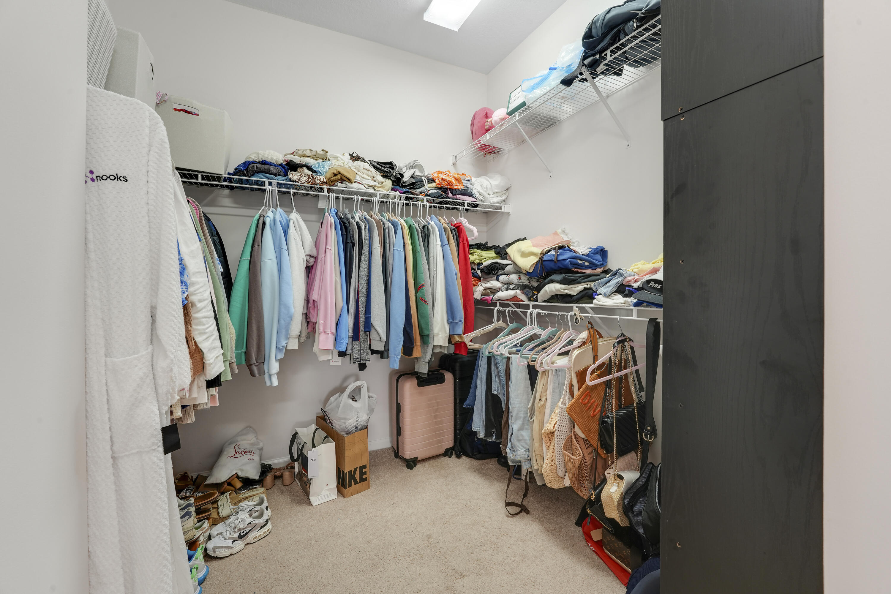 Walk-in closet featuring tiered wire shelving and neutral wall-to-wall carpeting