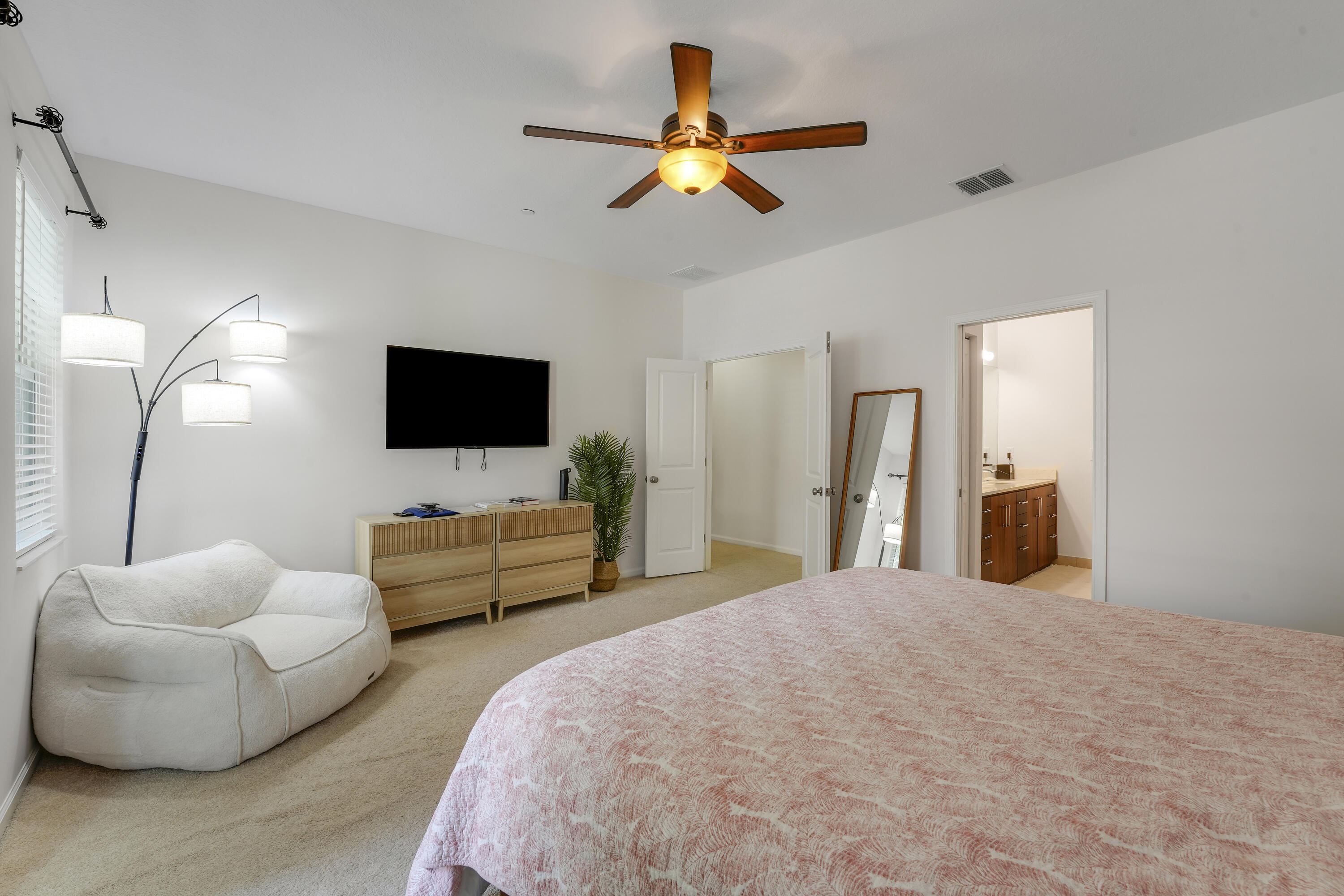 Neutral-toned room featuring carpeted flooring, a ceiling fan with integrated lighting, and multiple interior doors