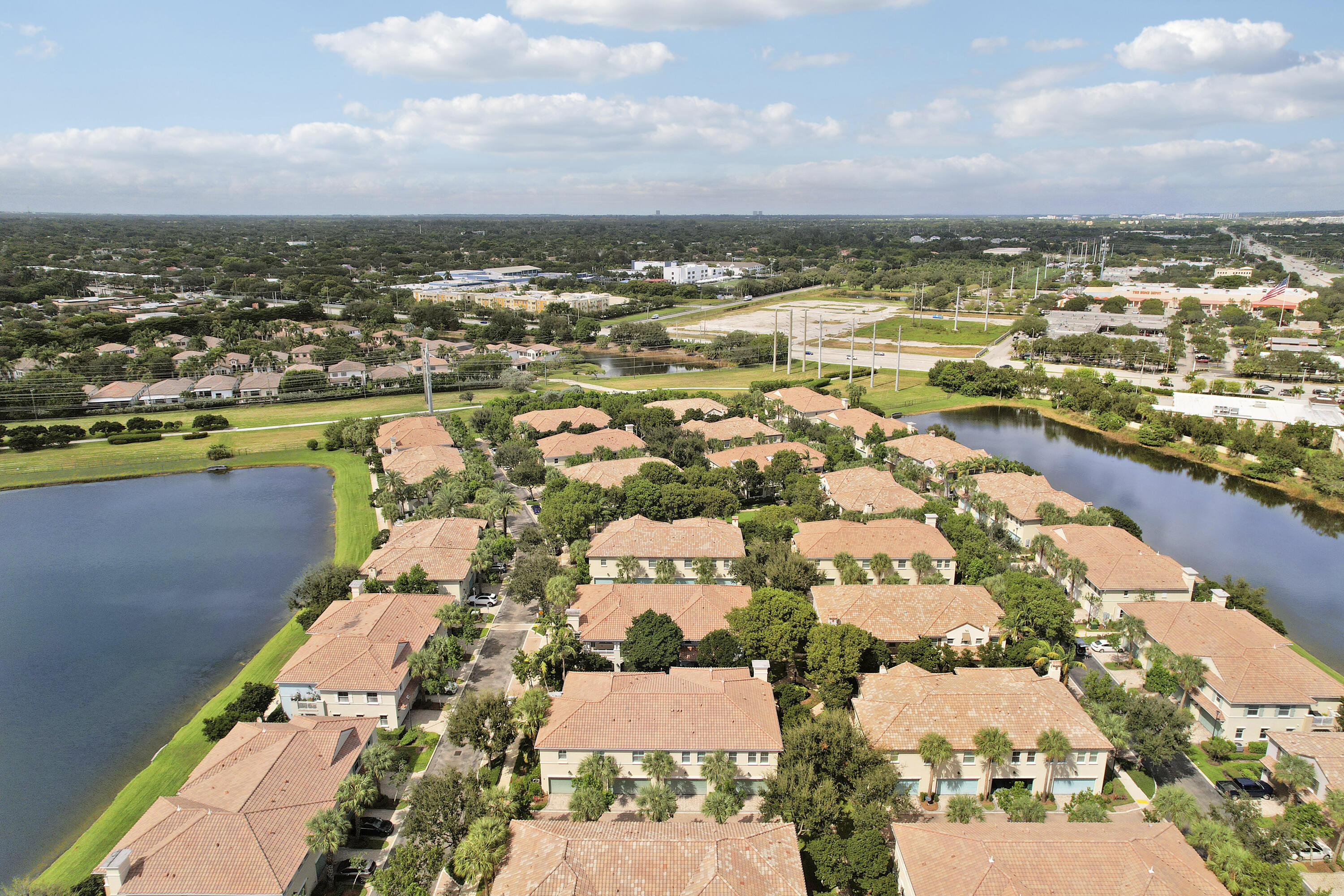 Aerial perspective of a multi-unit residential community featuring terracotta tile roofing, mature landscaping, and waterfront positioning