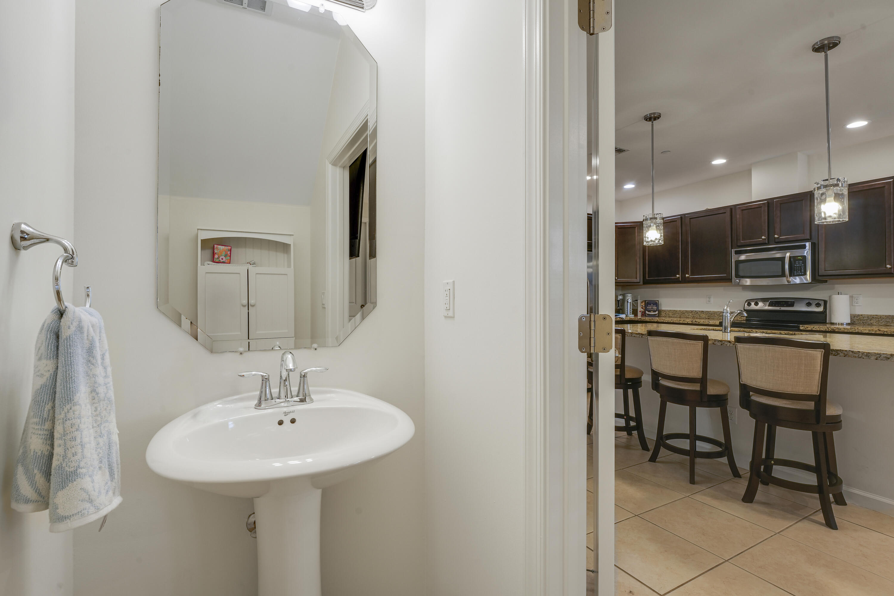 Powder room featuring a pedestal sink, polished chrome faucet, and beveled-edge mirror