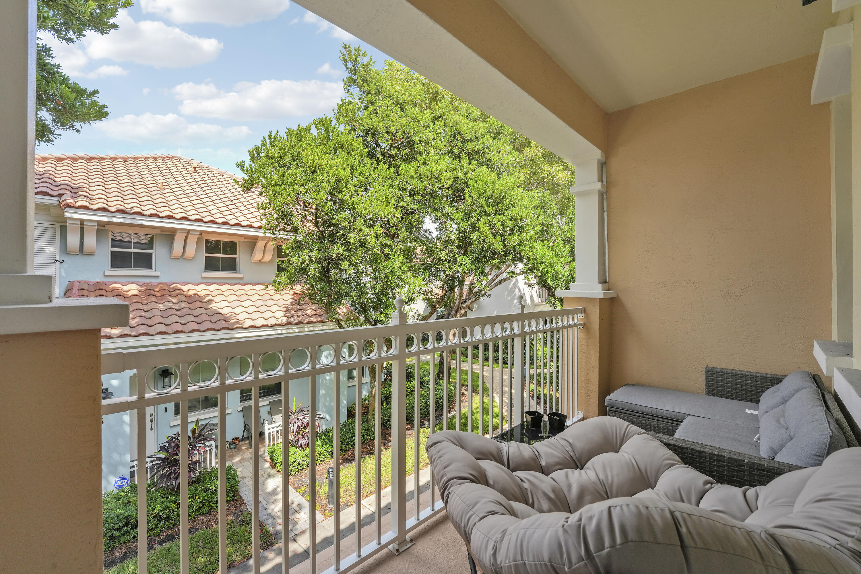 Covered balcony featuring white metal railings, architectural columns, and neutral-toned wall finishes
